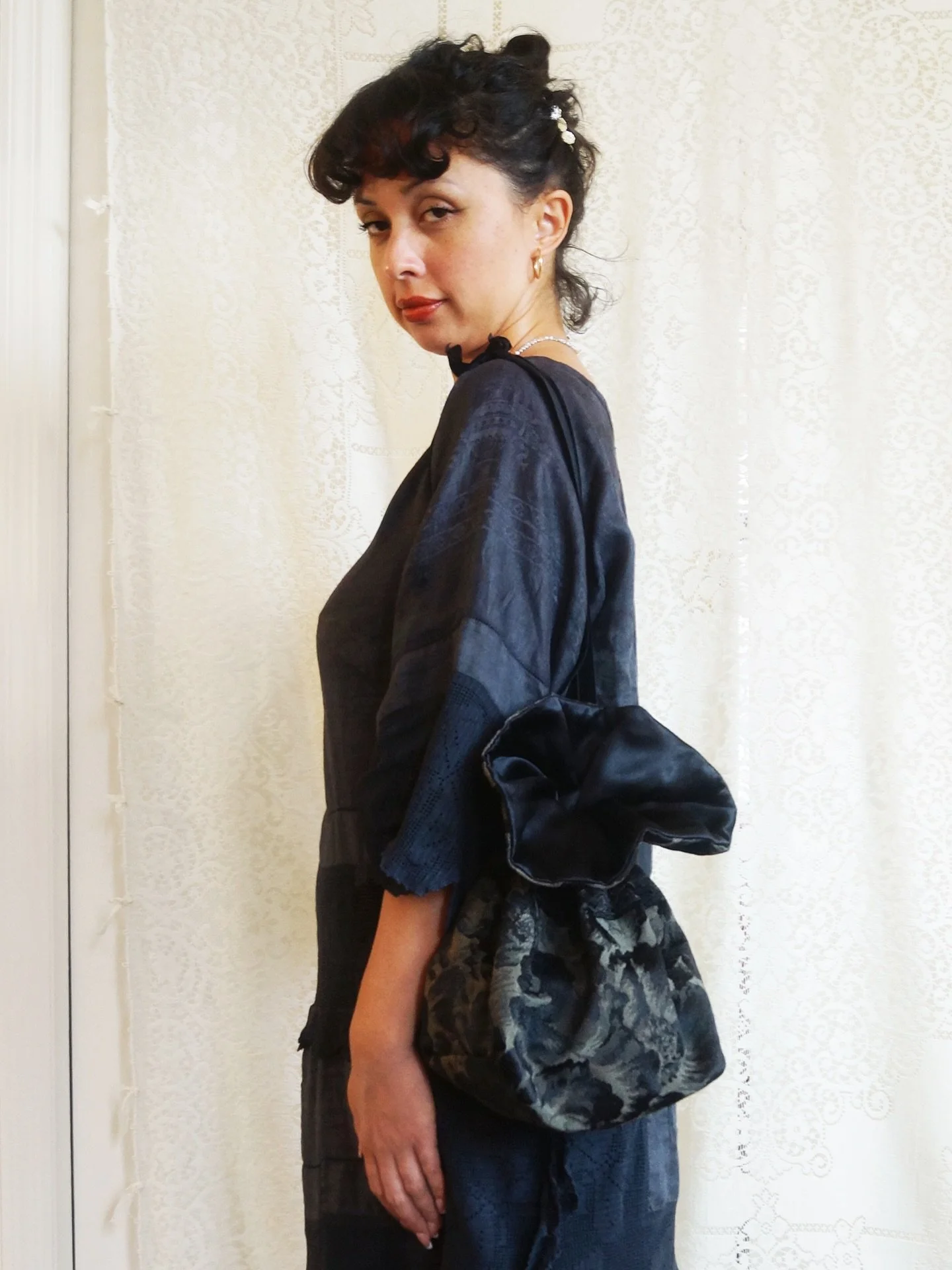 Victorian Noir Brocade Drawstring Bag
🖤
This bag opens like a night-blooming flower&mdash;petals of black satin unfurling at the rim, catching the light with a quiet shimmer. The body is sewn from vintage brocade, its shadowy florals drifting across