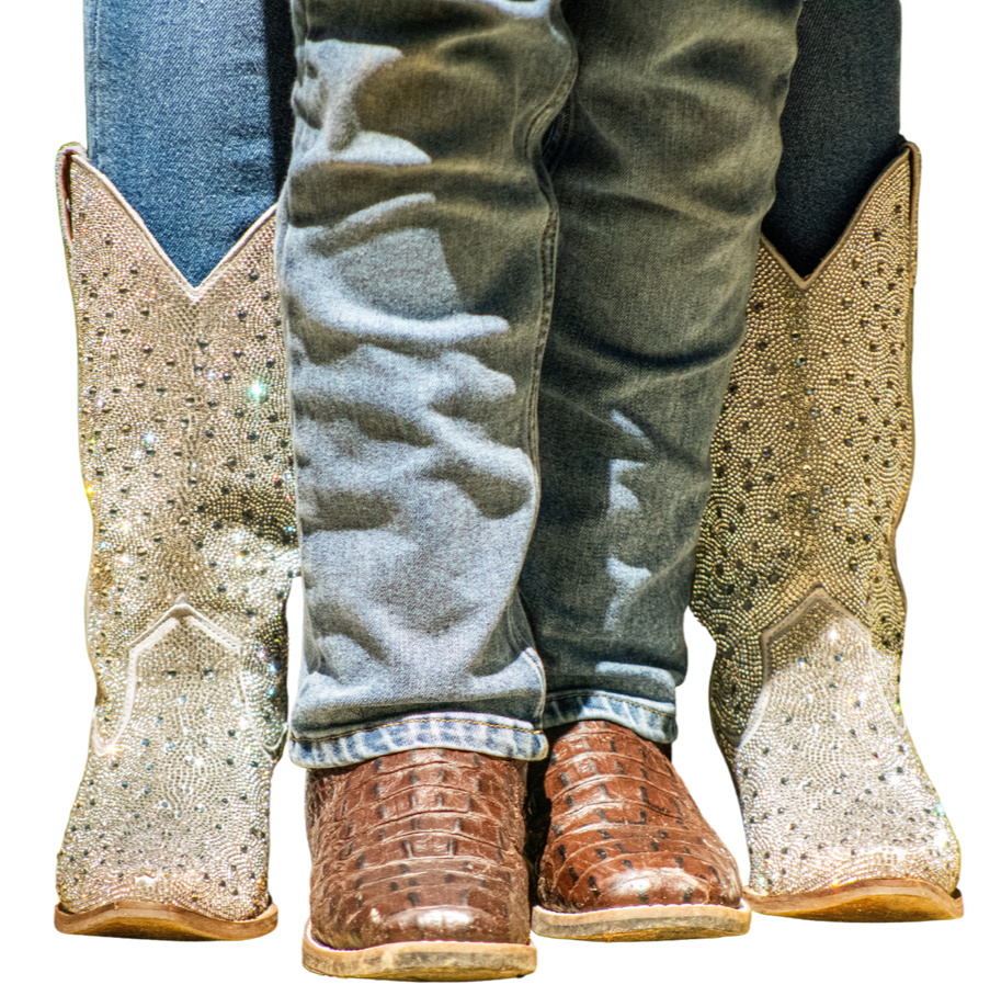Person wearing dark jeans, brown cowboy boots, and crystal-studded cowboy boots.