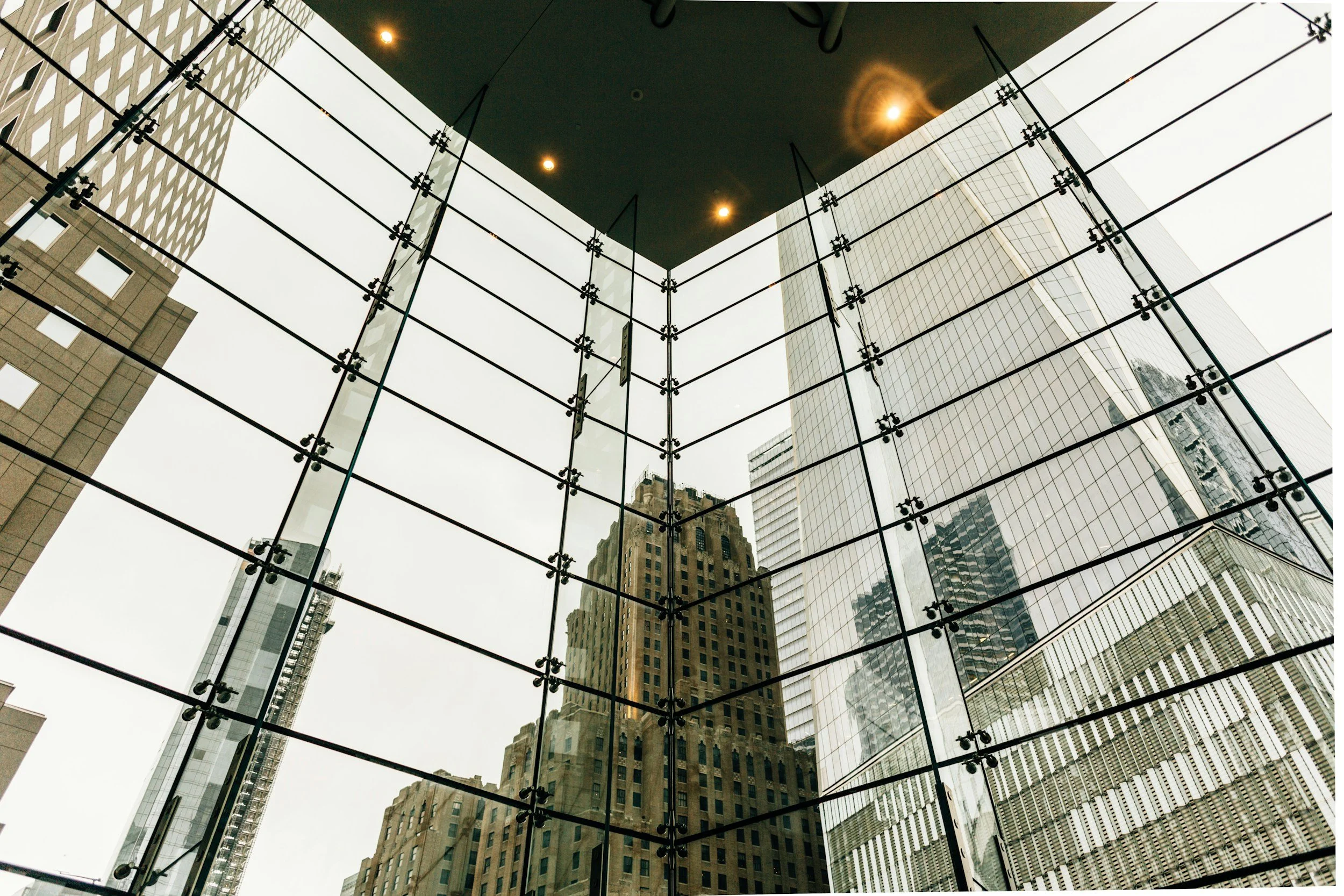 View of city skyscrapers seen through glass window with black frames and reflections.