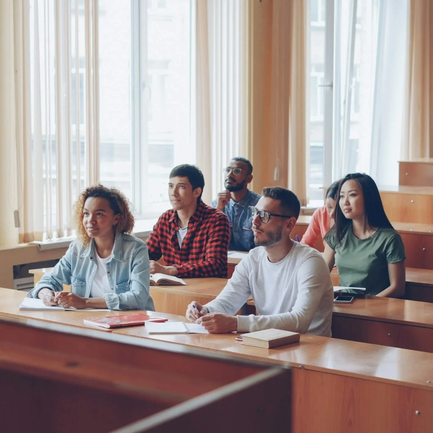 A diverse group of students sitting in a classroom, attentively listening during a lecture.