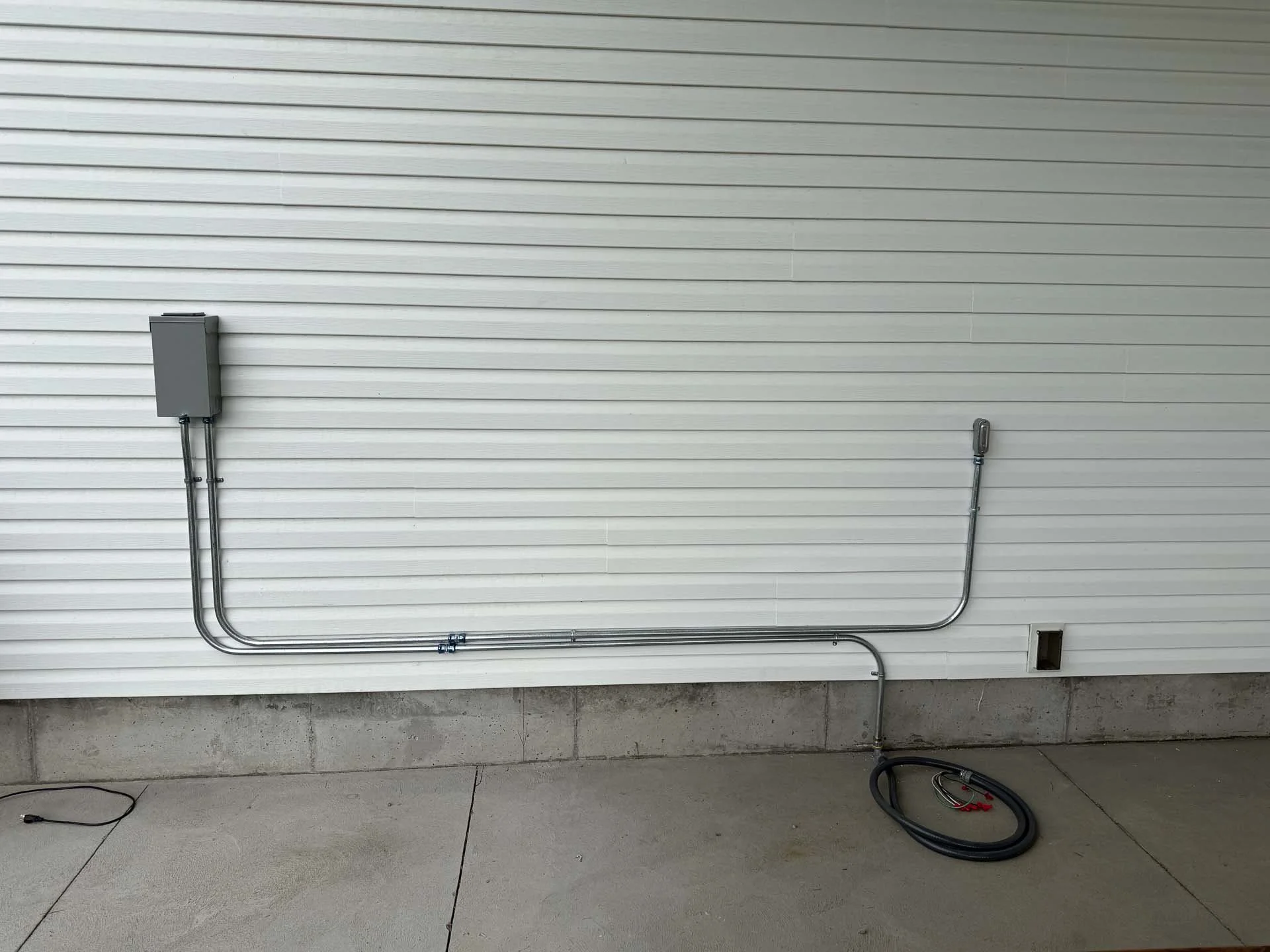 Electrical panel on a house exterior wall with cables and wiring.