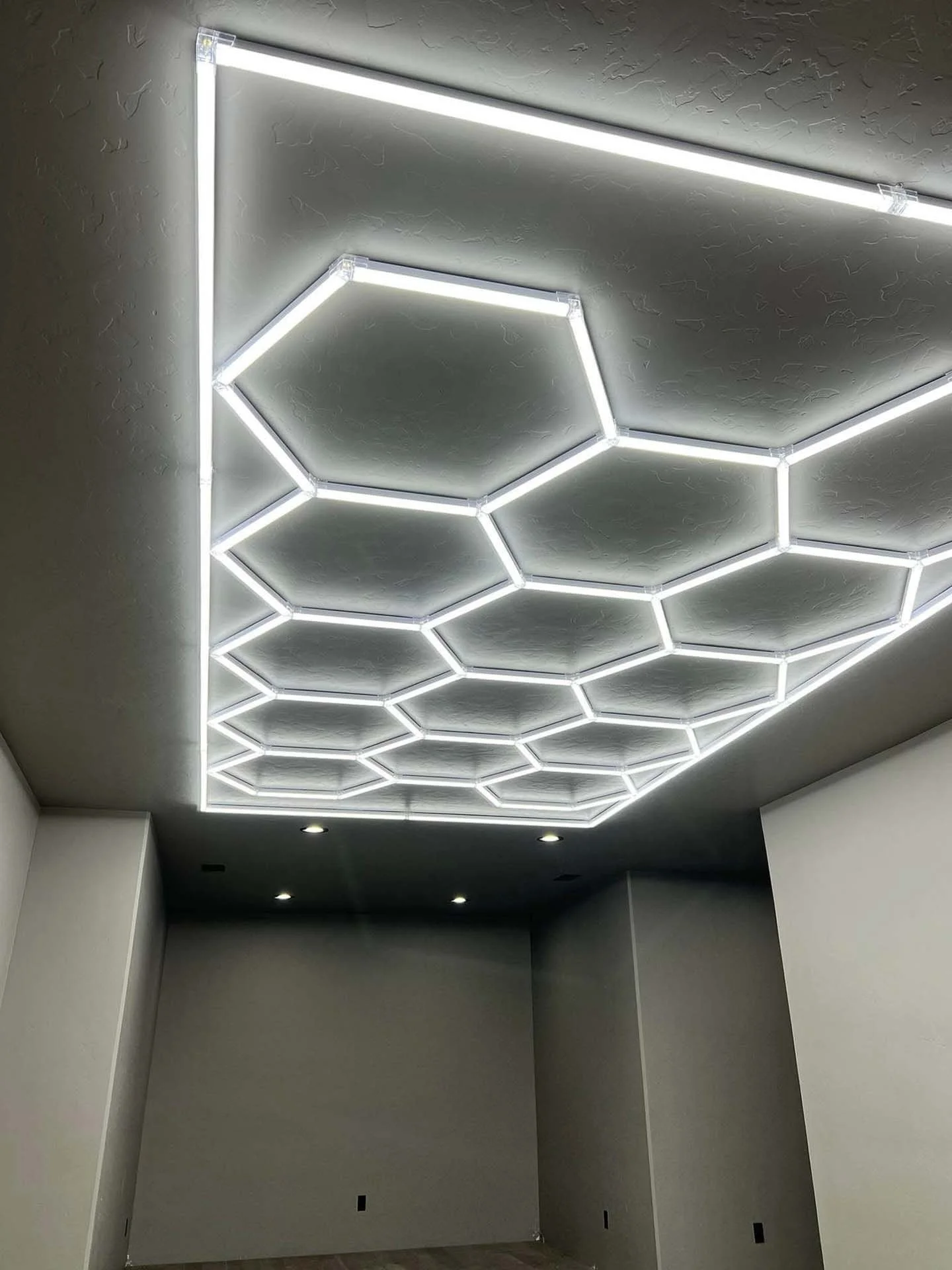 Ceiling with modern hexagonal LED light fixtures arranged in a honeycomb pattern