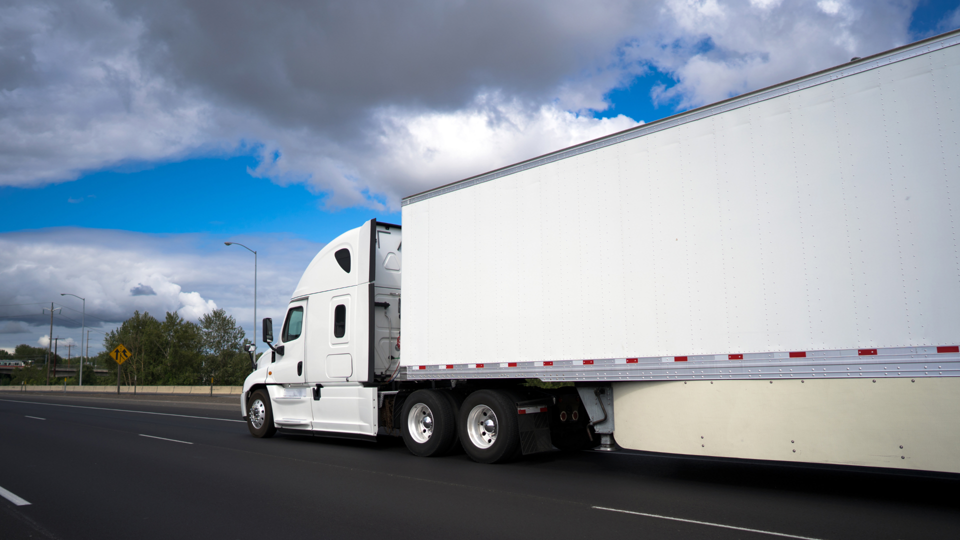 Commercial truck driving on highway for small fleet insurance pricing guide