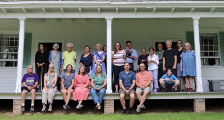 Friendly  people of all ages sit on the front porch outside the historic Cornwall historic Quakers Meetinghouse