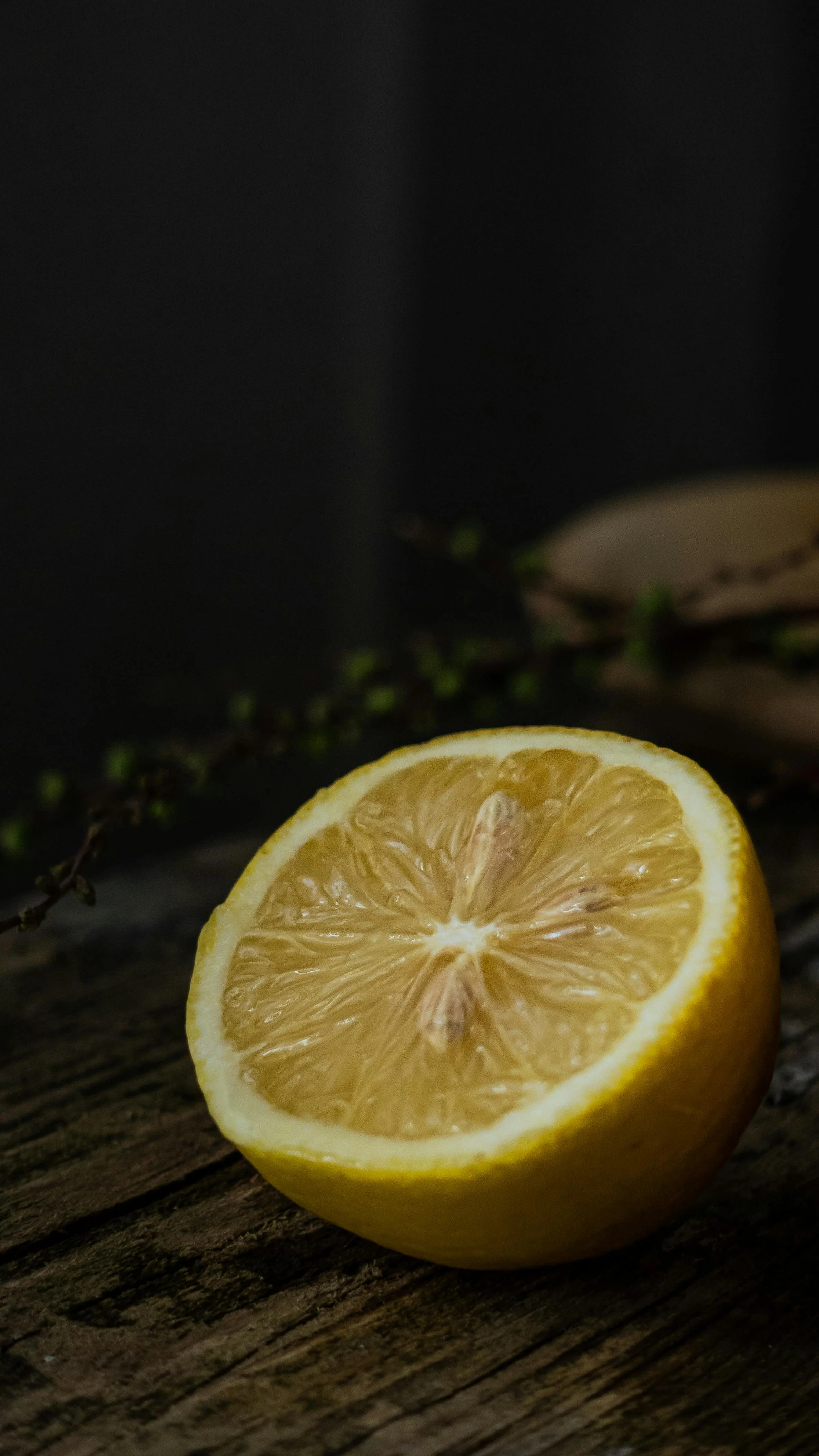 Half-cut lemon on a wooden surface with a dark background.