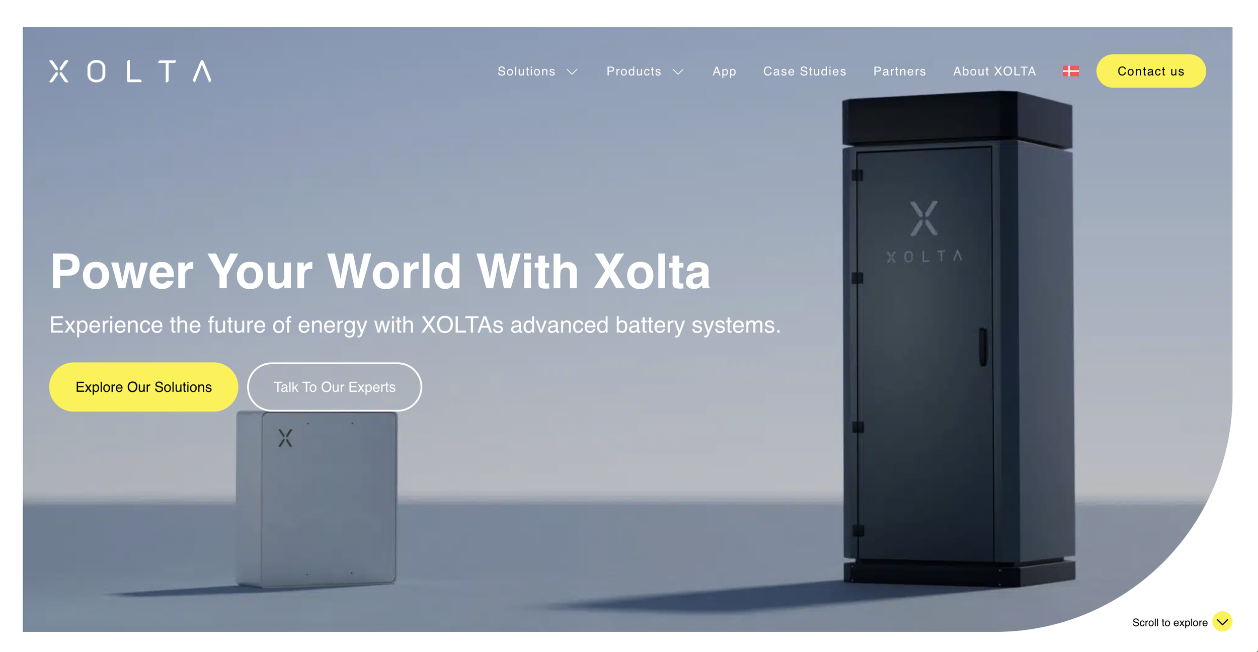 Xolta website homepage showing two energy storage units, a smaller white unit and a larger black unit, against a light blue background with navigation links and buttons for exploring solutions and talking to experts.