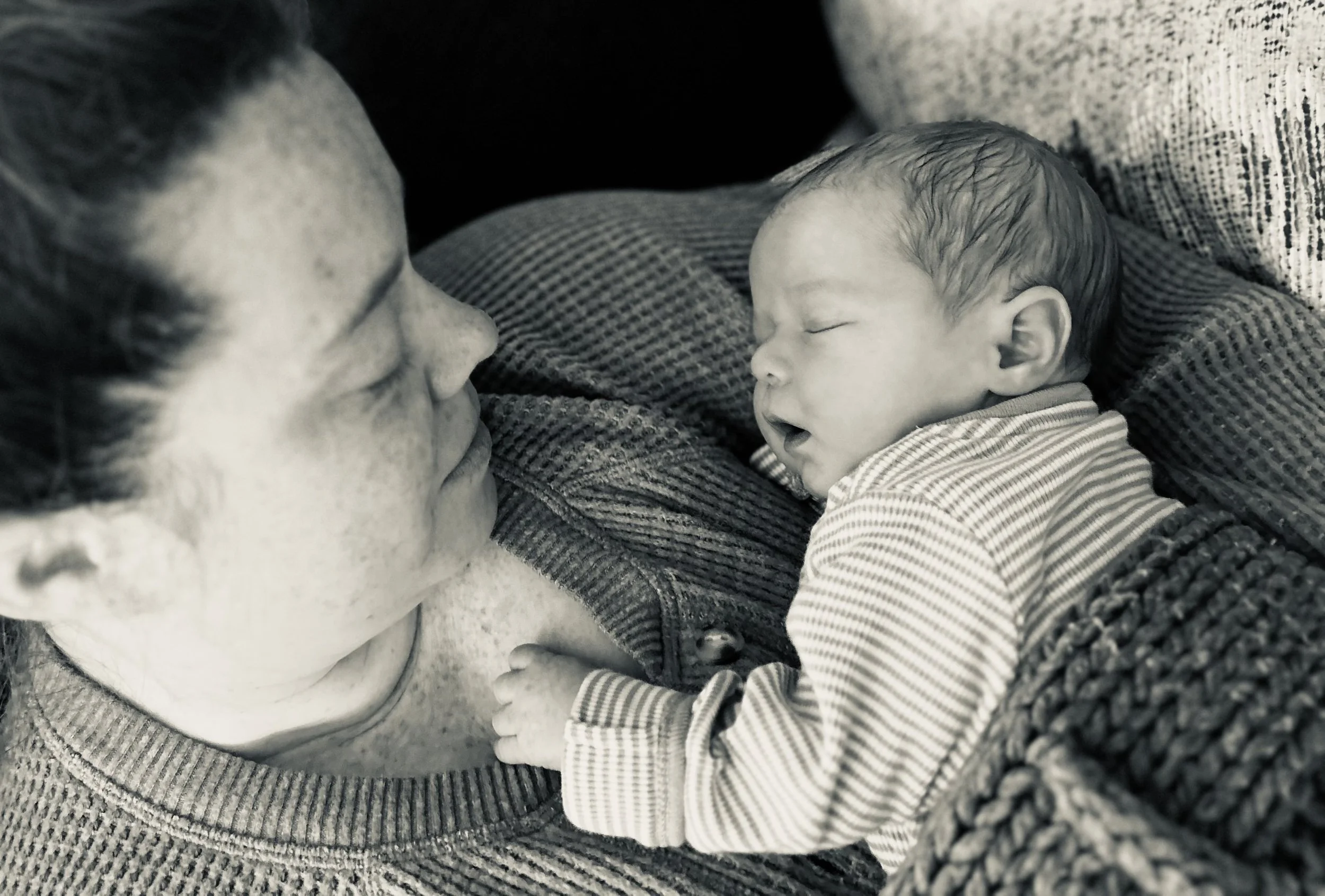 A woman holding a sleeping newborn baby who is resting on her chest.