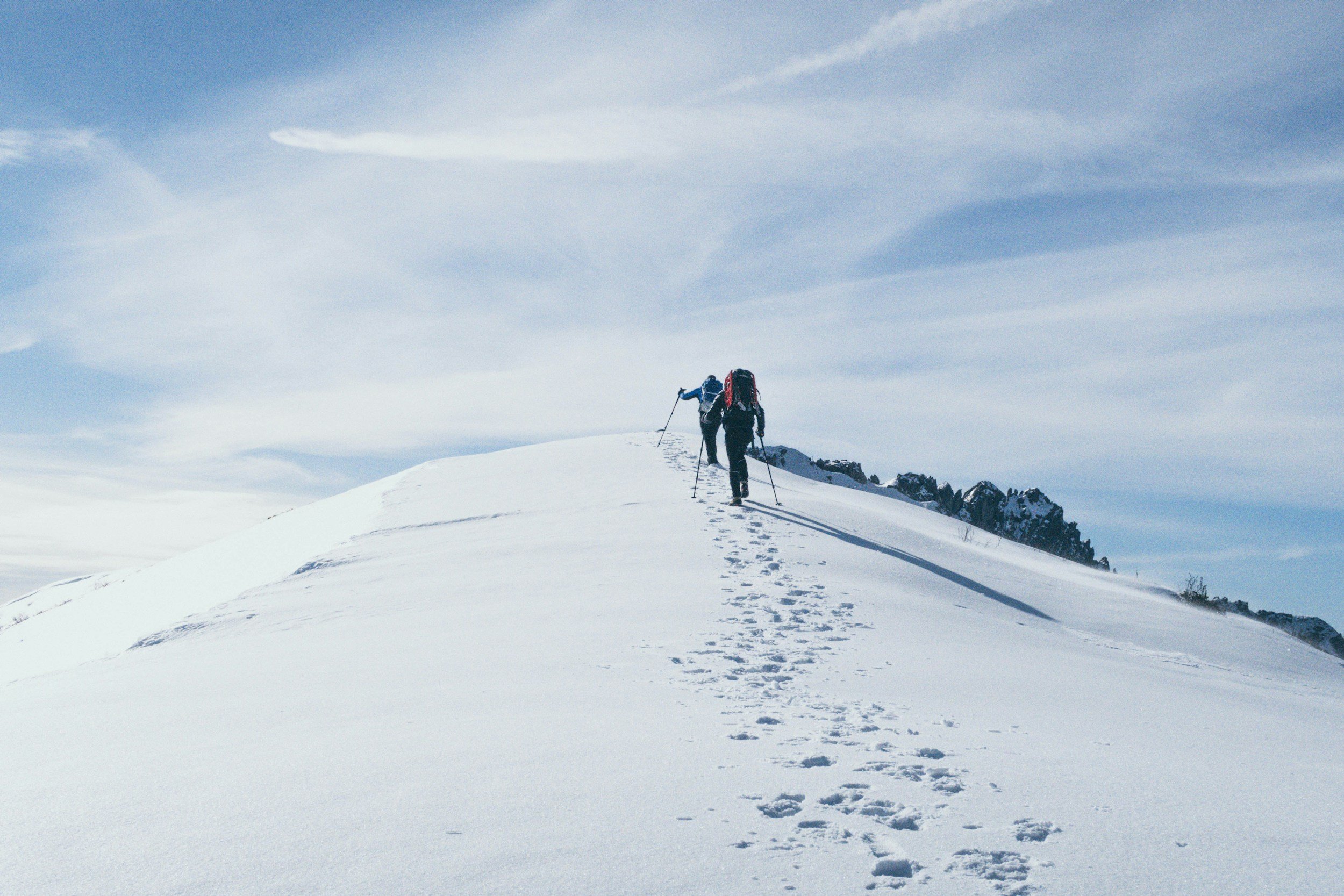 A silhouette of a person climbing a grassy hill against a bright sky.