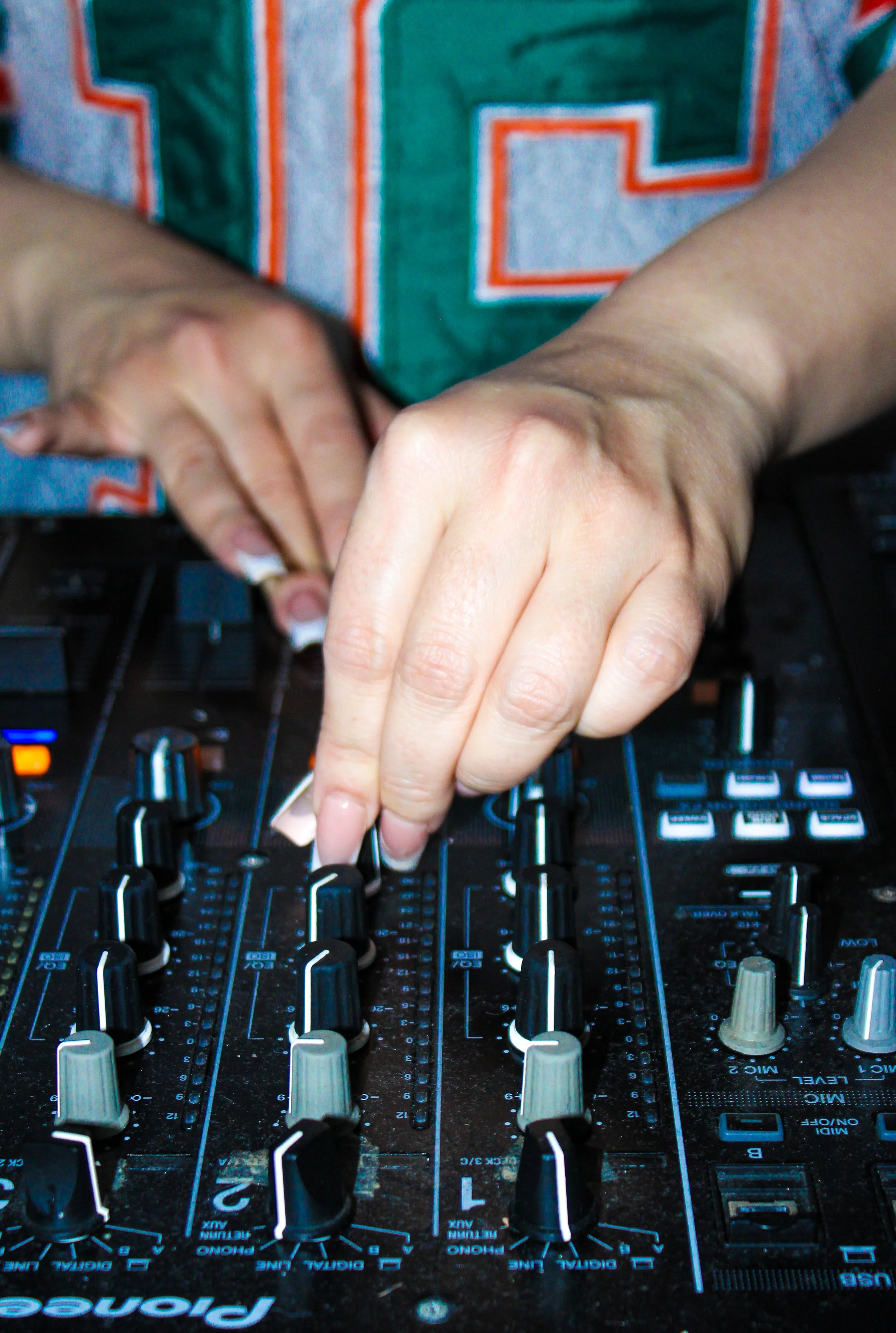 Close-up view of hands adjusting controls on a DJ mixing console.