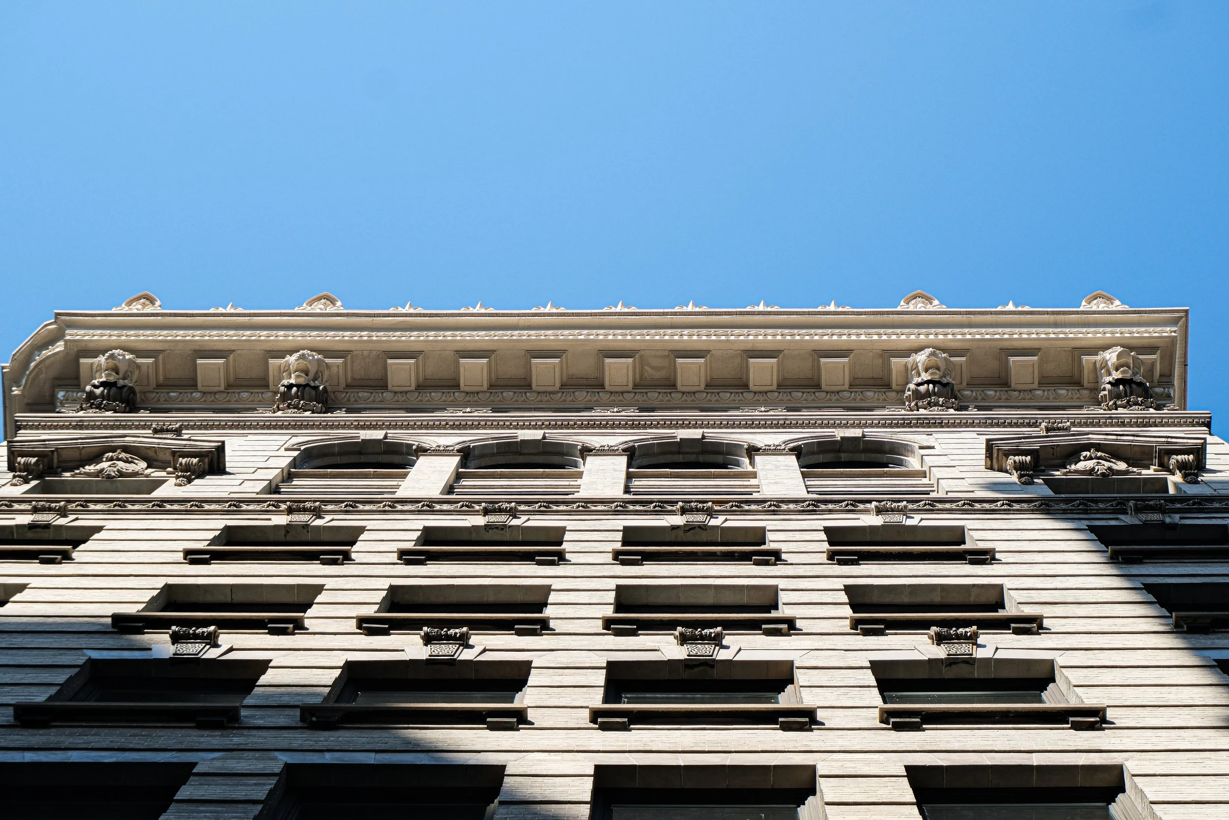Looking up at a historic building with ornate architectural details against a clear blue sky.