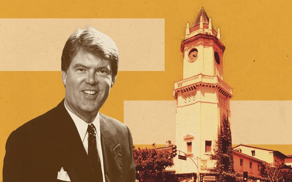 A man in a suit smiling, standing in front of a building with a tall clock tower.