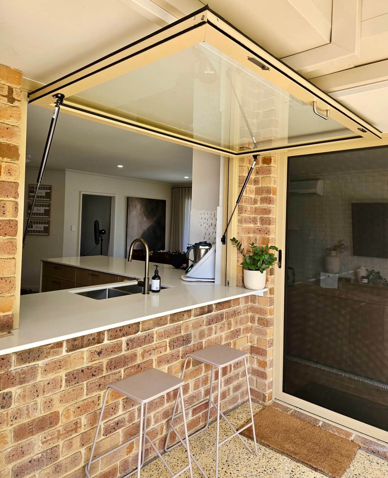 Large servery window built in to kitchen brick wall.