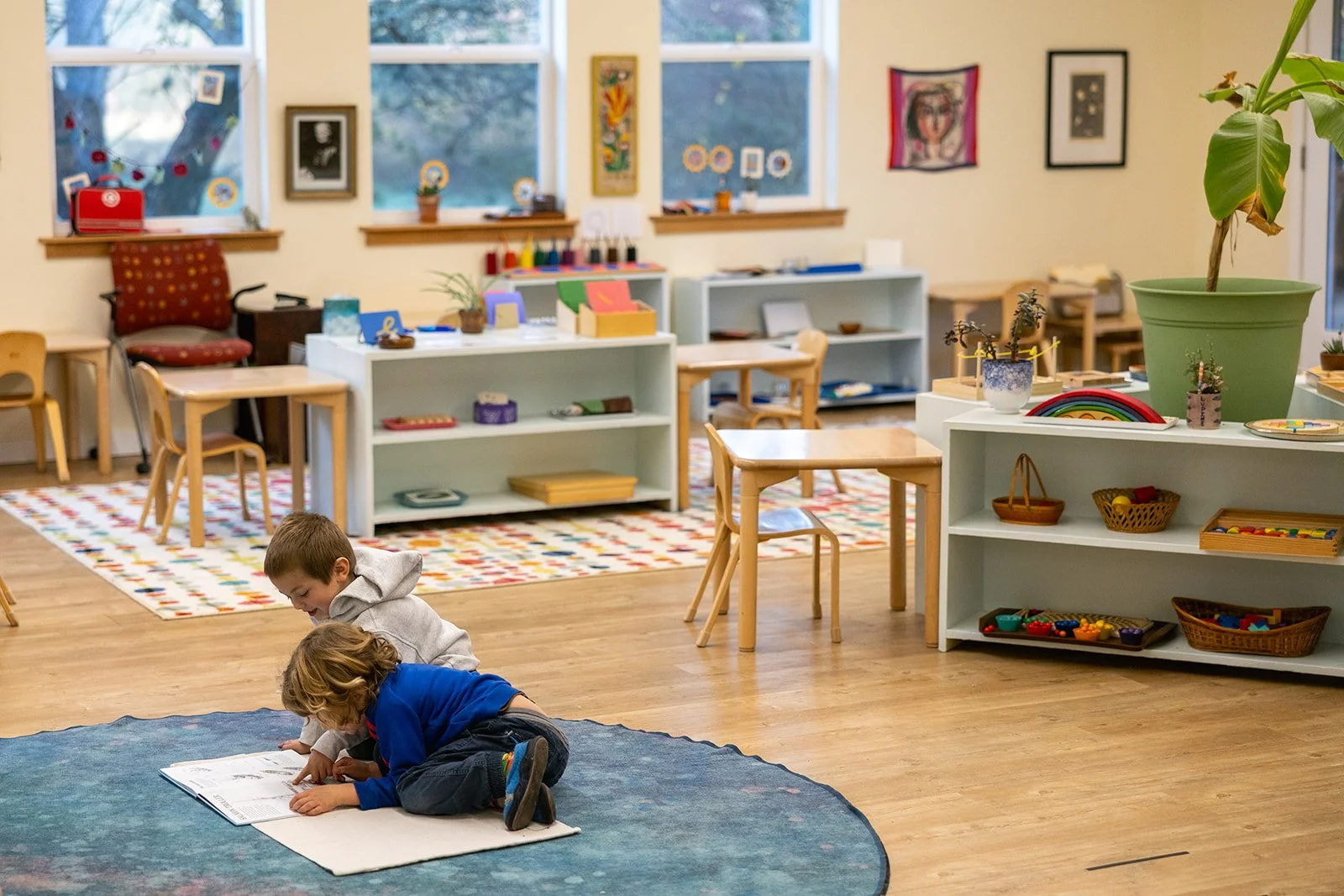 Two preschoolers sitting on a blue carpet looking at a book