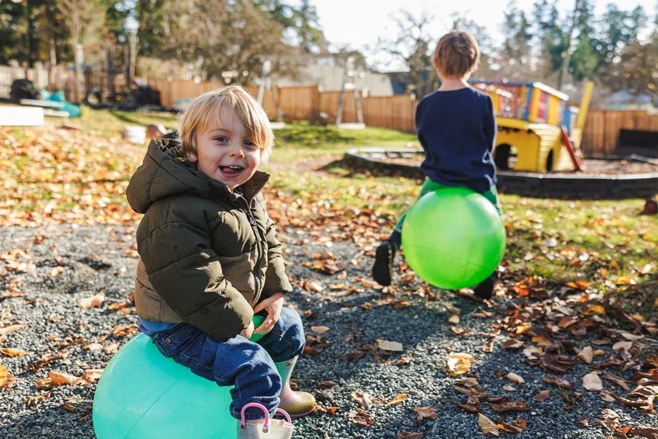 Two preschoolers on bouncy balls wearing jackets