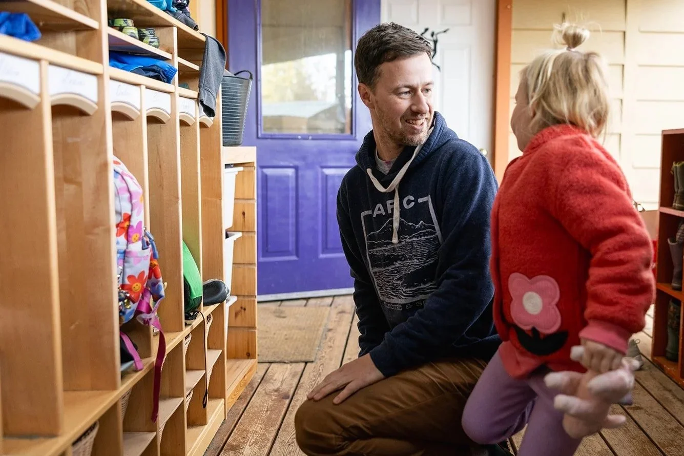 Father kneeing while saying goodbye to child at preschool