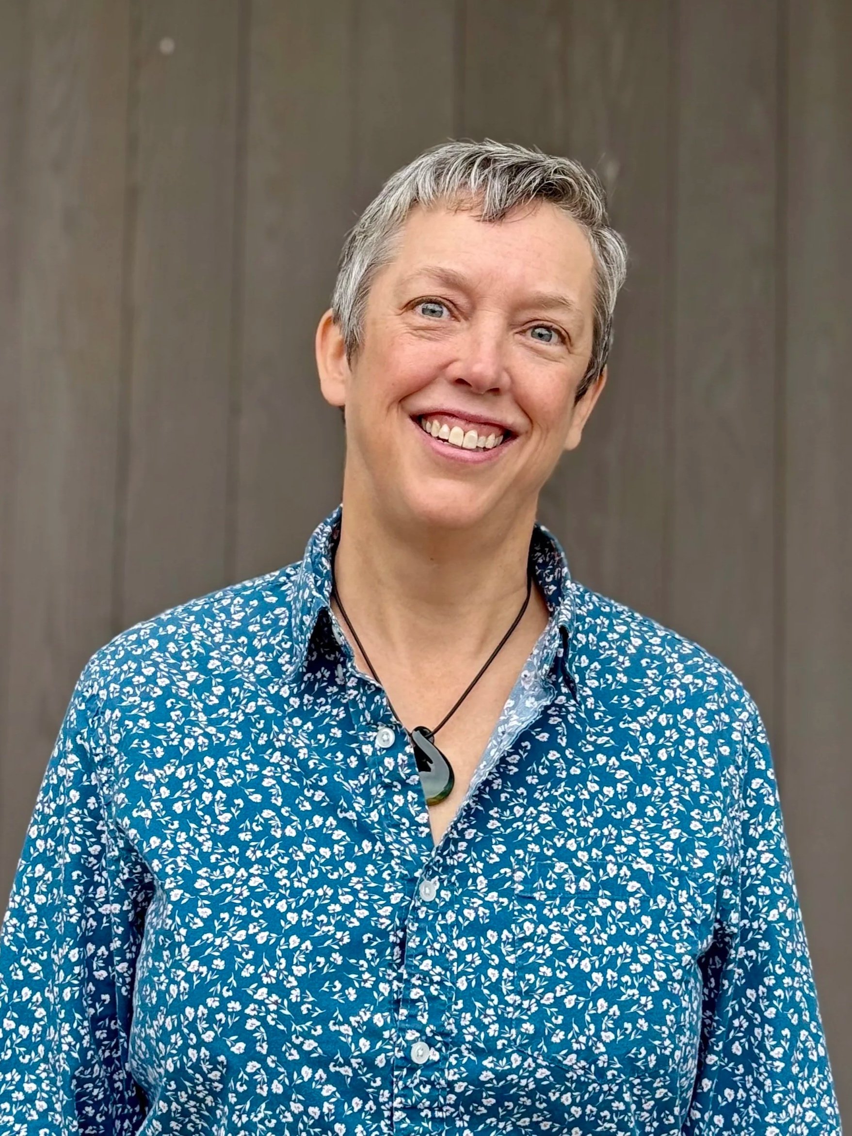 Portrait of person with short salt and pepper hair wearing blue shirt pattern with small flowers