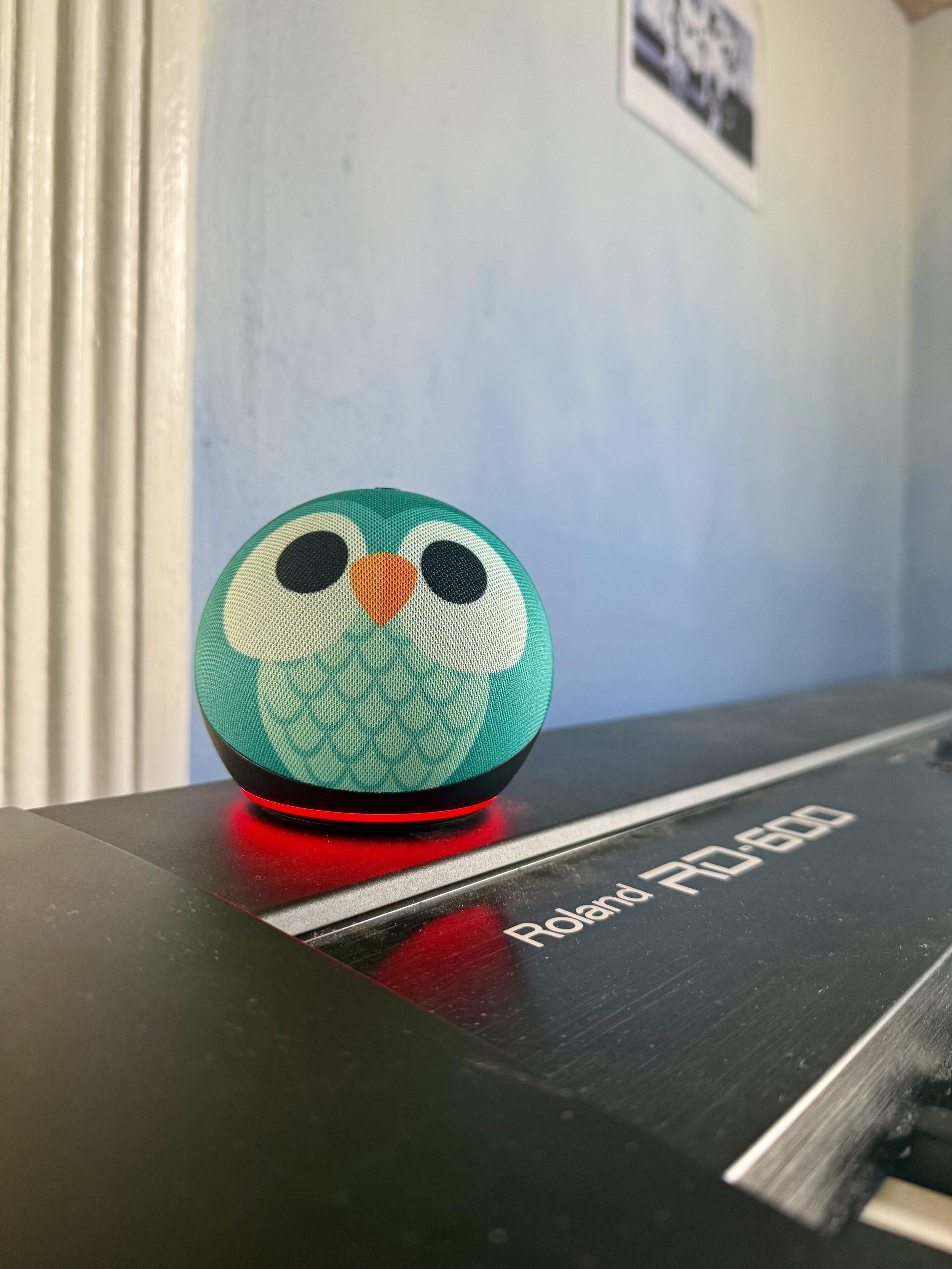 Small spherical speaker with an illustration of a teal bird on it
