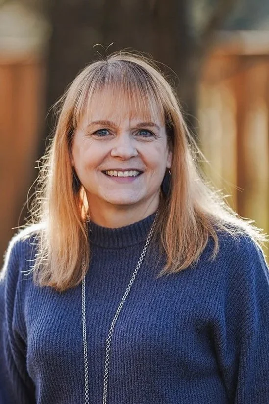 Portrait of person with smiling with long hair and dark blue sweater