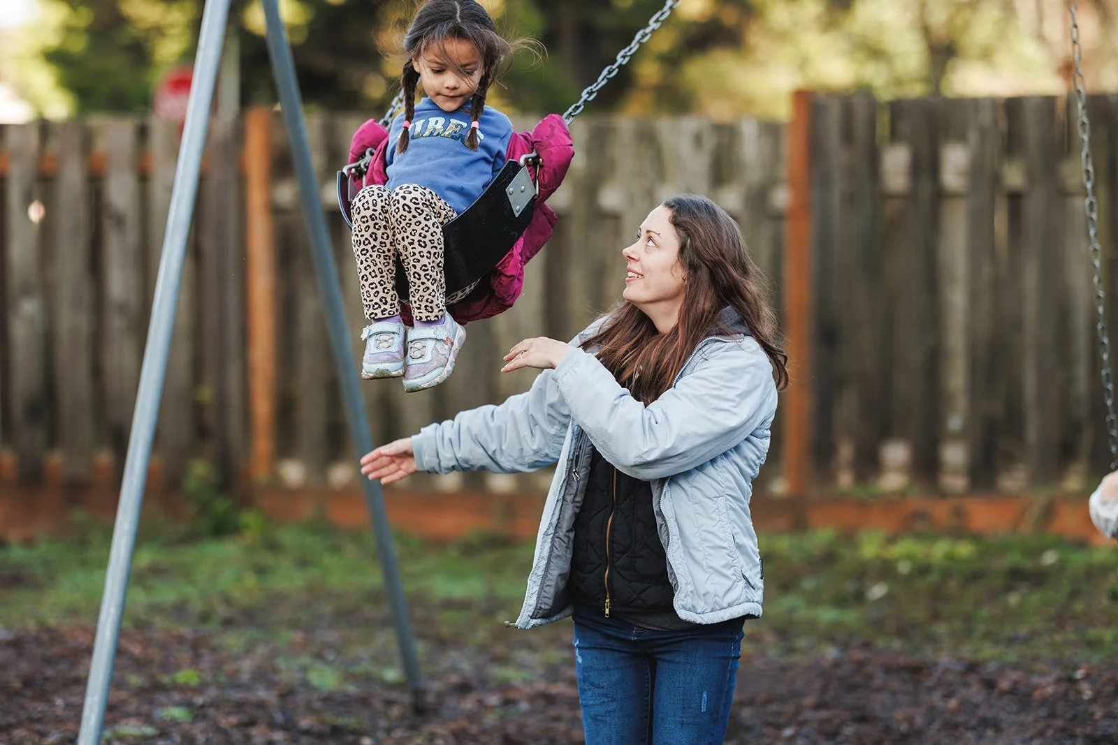 Teacher pushing child on swing. The teaches is looking up and the child looking down