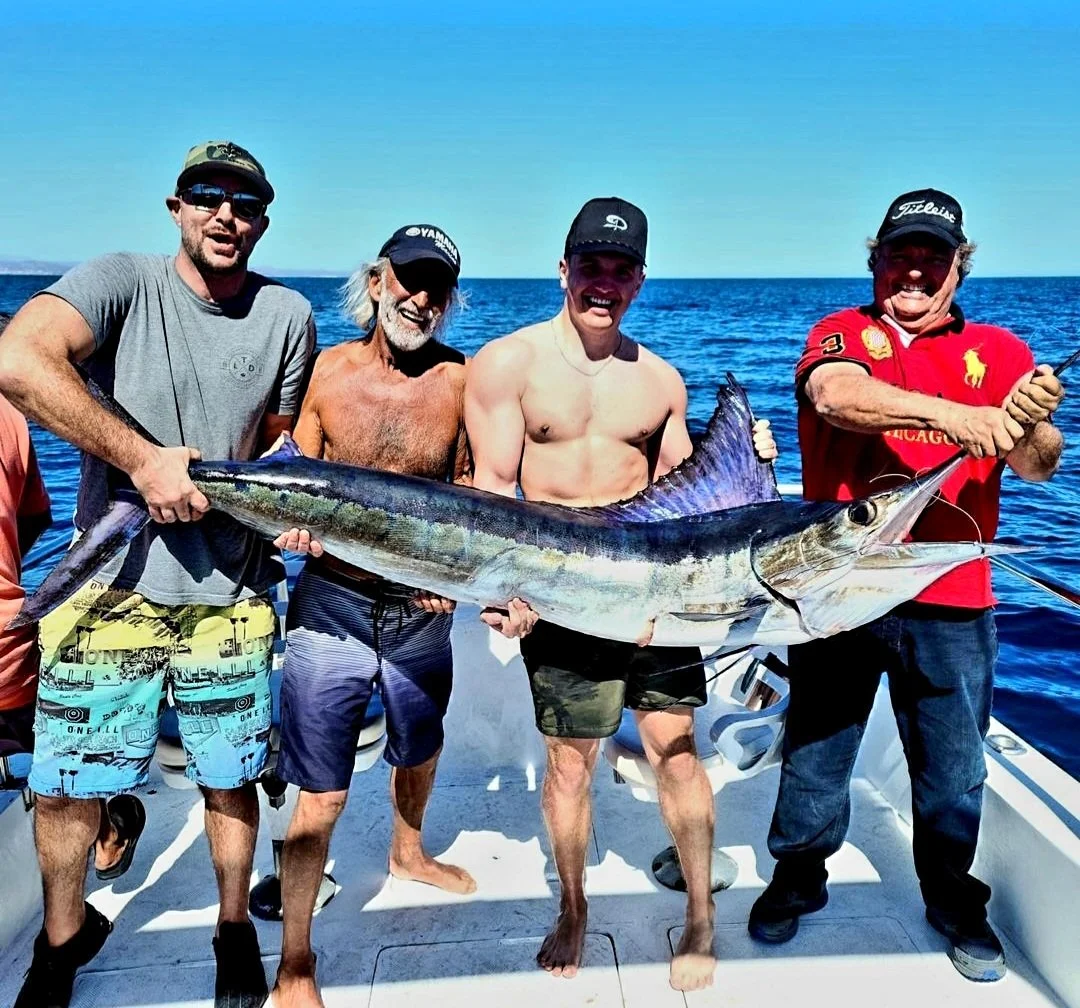 Four men holding a large fish on a boat in the ocean | The Marlin Hunter Fishing Charter Day Trip Cabo