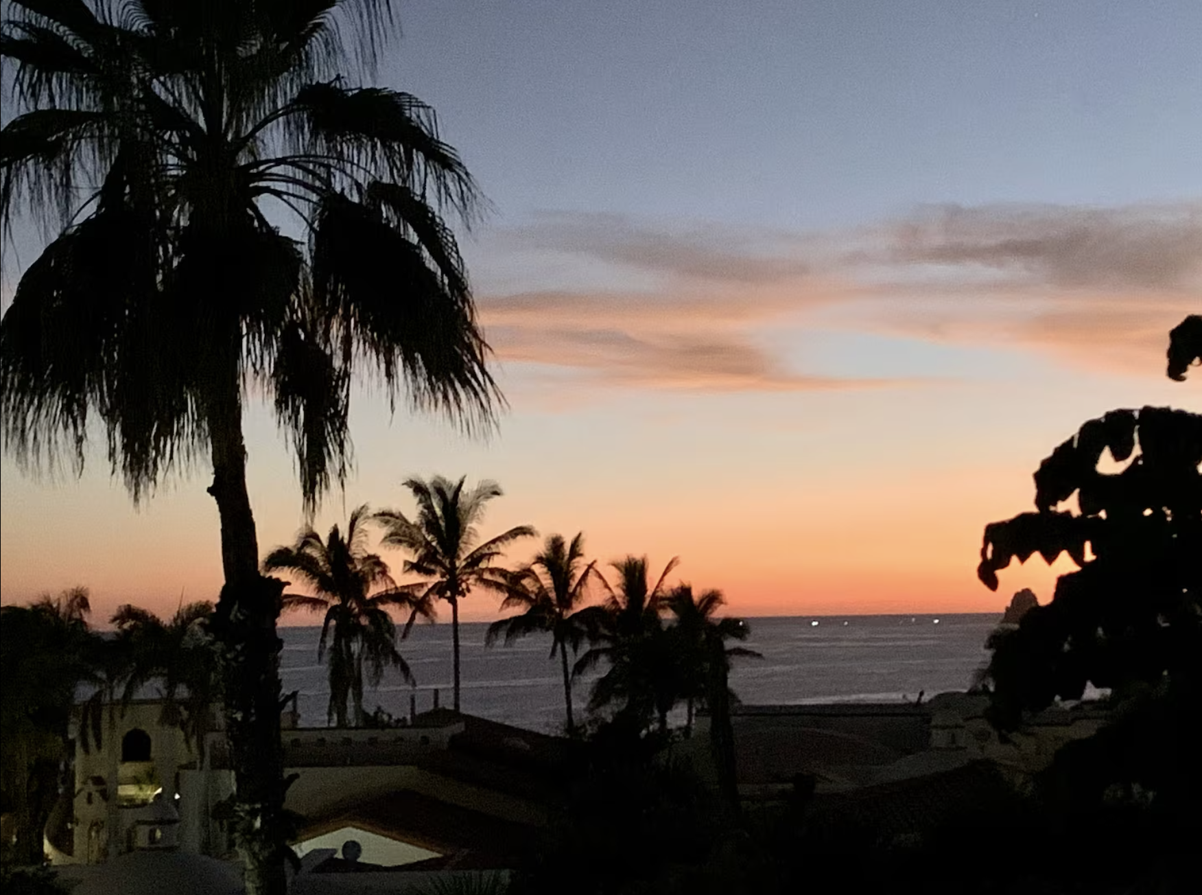 Three people fishing on rocky shoreline at sunset, with calm ocean and colorful sky in background. | Fishing trip in Baja 