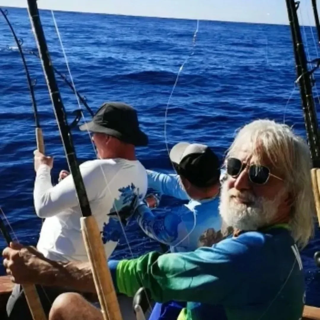 Three men fishing from a boat on the ocean, with deep blue water and fishing rods. The Marlin Hunter fishing charters