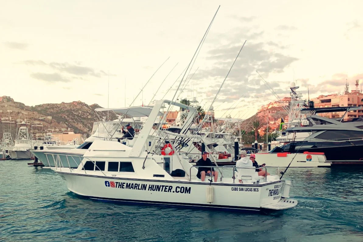 A white fishing charter boat speeding through the famous Cabo ocean landscape. | The Marlin Hunter Fishing Charters