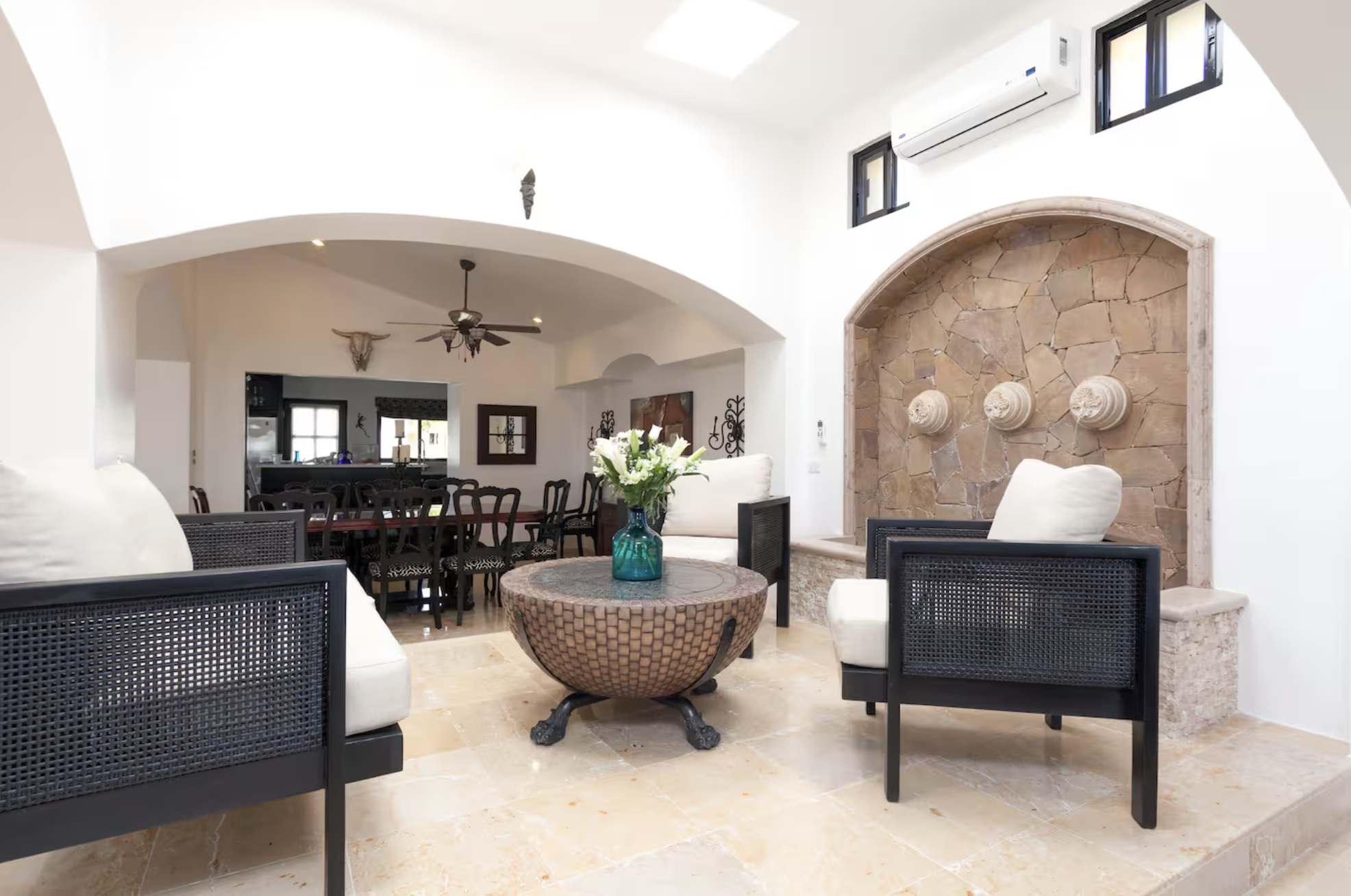 Living room with white walls, black furniture, stone wall feature, decorative wall niches, and high ceiling with a ceiling fan.