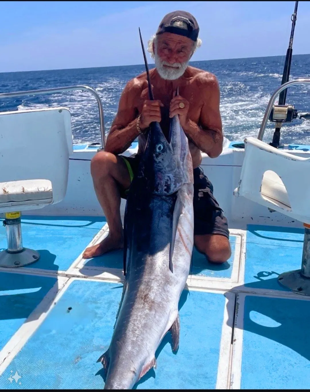 The Marlin Hunter, Frank, kneeling on The Marlin Hunter fishing charter, holding the catch of the day. 