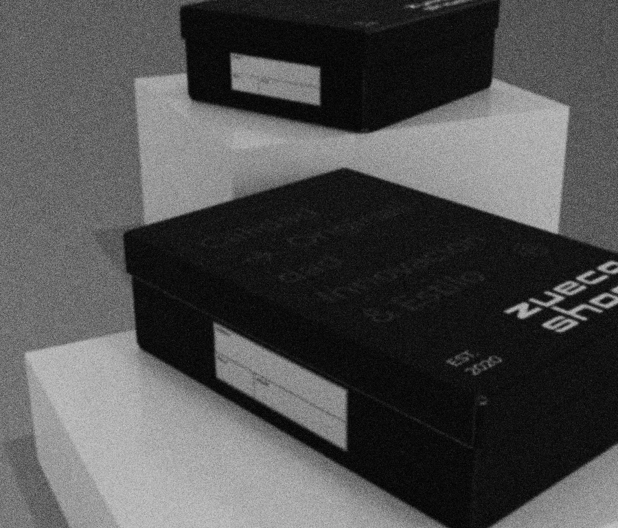 Two black boxes, one on top of a white cube and the other on a lower white surface, with blank labels on the sides.