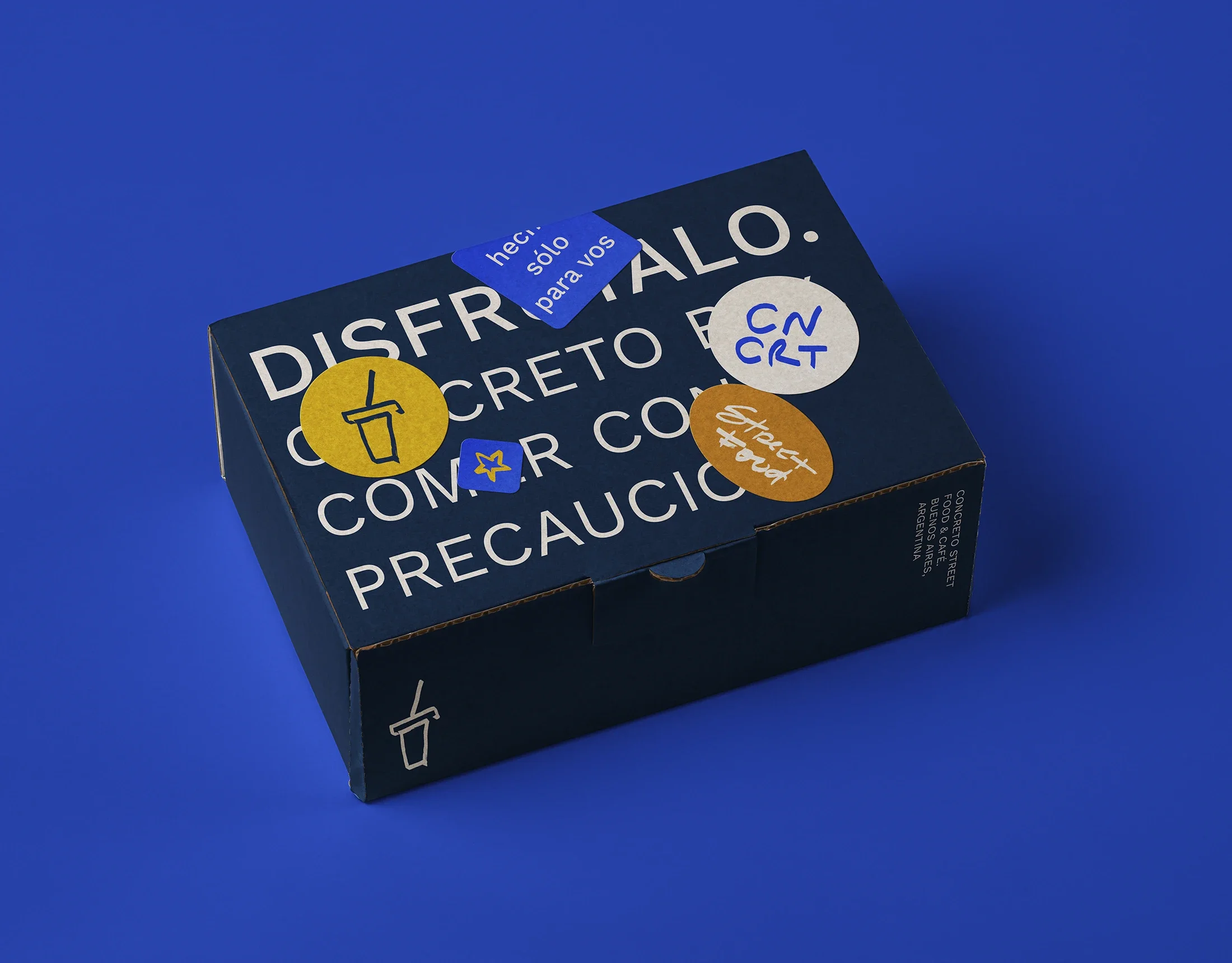A blue fast food box full of stickers that show Concreto's branding, a street food brand.