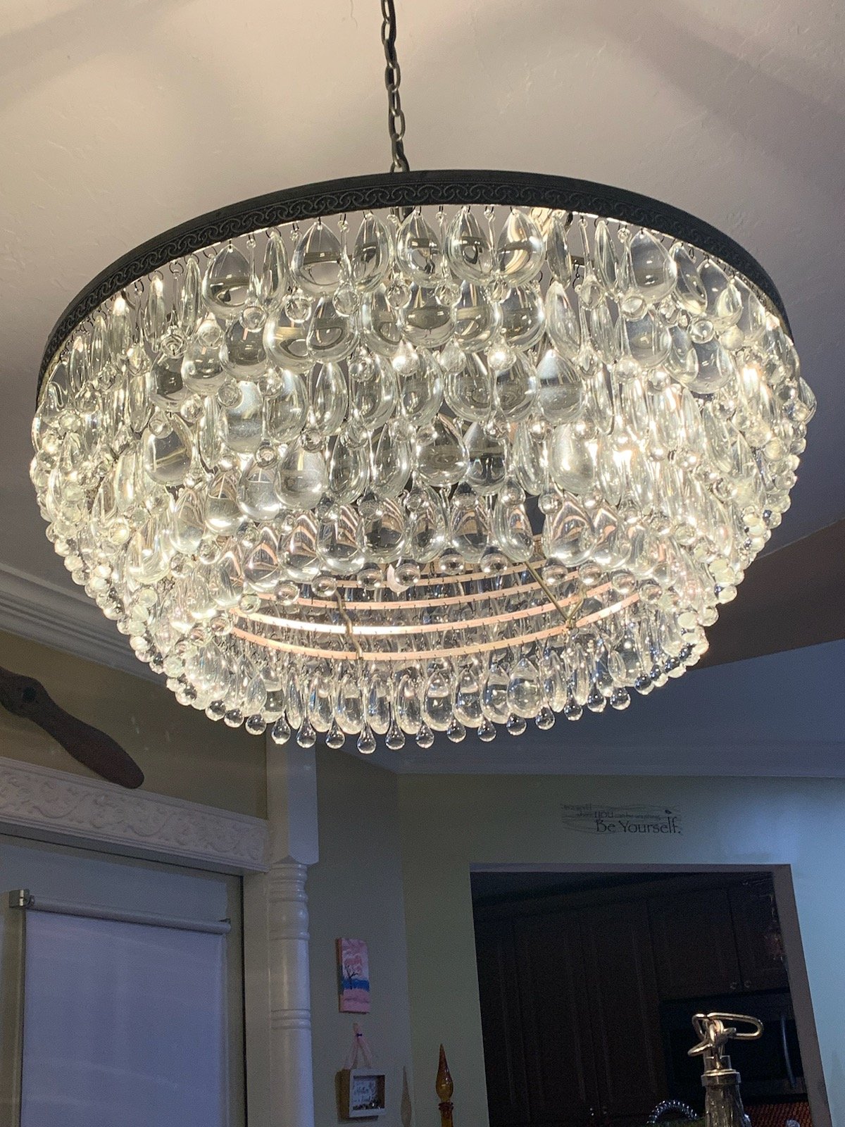 A large, round crystal chandelier hanging from the ceiling in a home interior.
