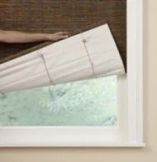 Person installing or adjusting a window blind or shade in a window frame