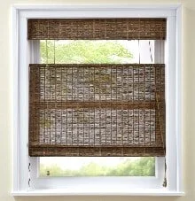 Window with woven bamboo or wicker shades partially rolled down.