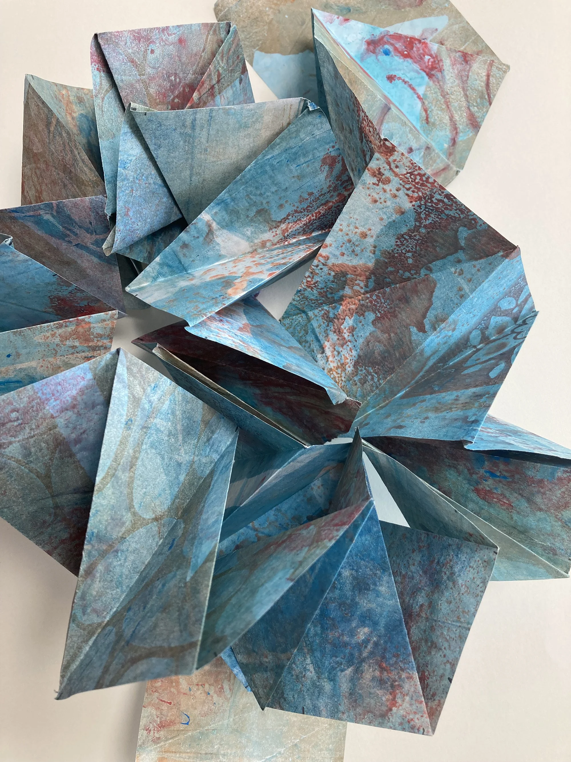 “Progression - Ode to Sam Gilliam” is an installation piece created with monotypes on paper. Depending on the display area it can fit into a two foot cubic space. The paper is folded in polygon swirls to revel multiple colors and patterns inspired by