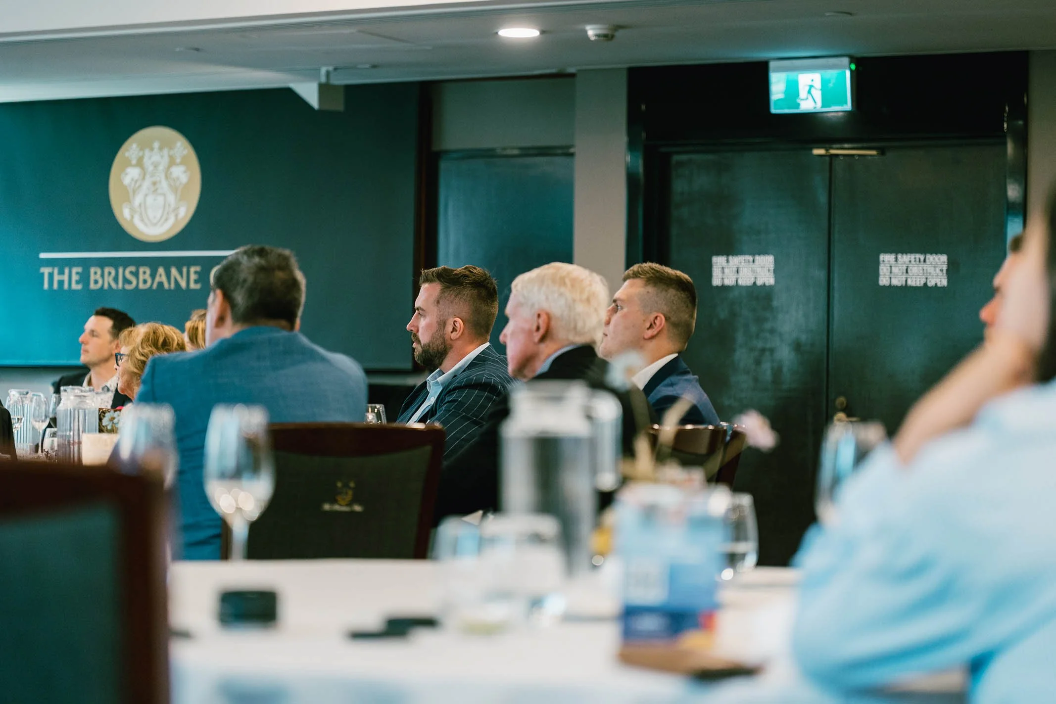 Business professionals seated at a conference table in a formal setting at The Brisbane, listening to a presentation or speaker.