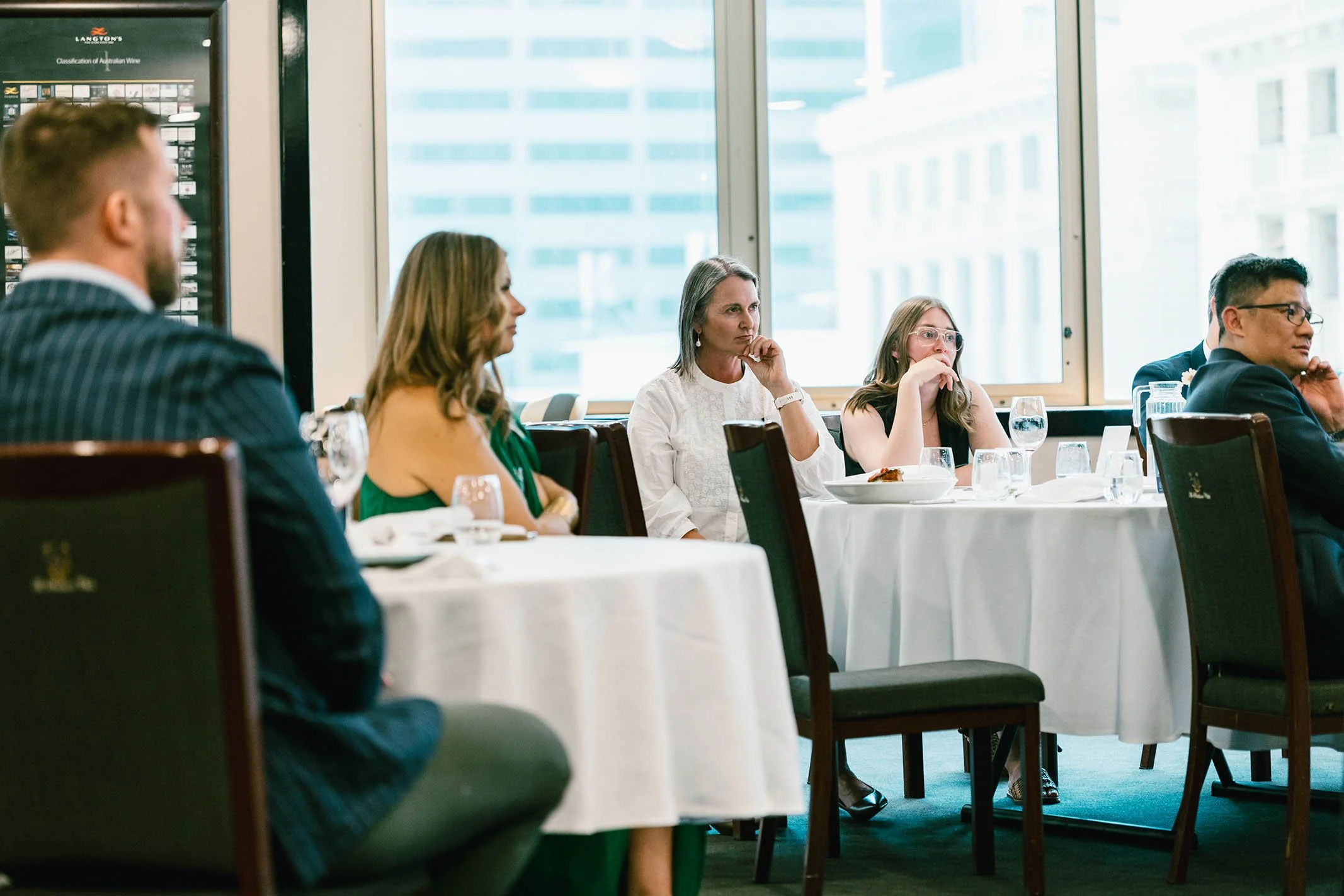 People sitting at round tables in a conference room listening attentively.