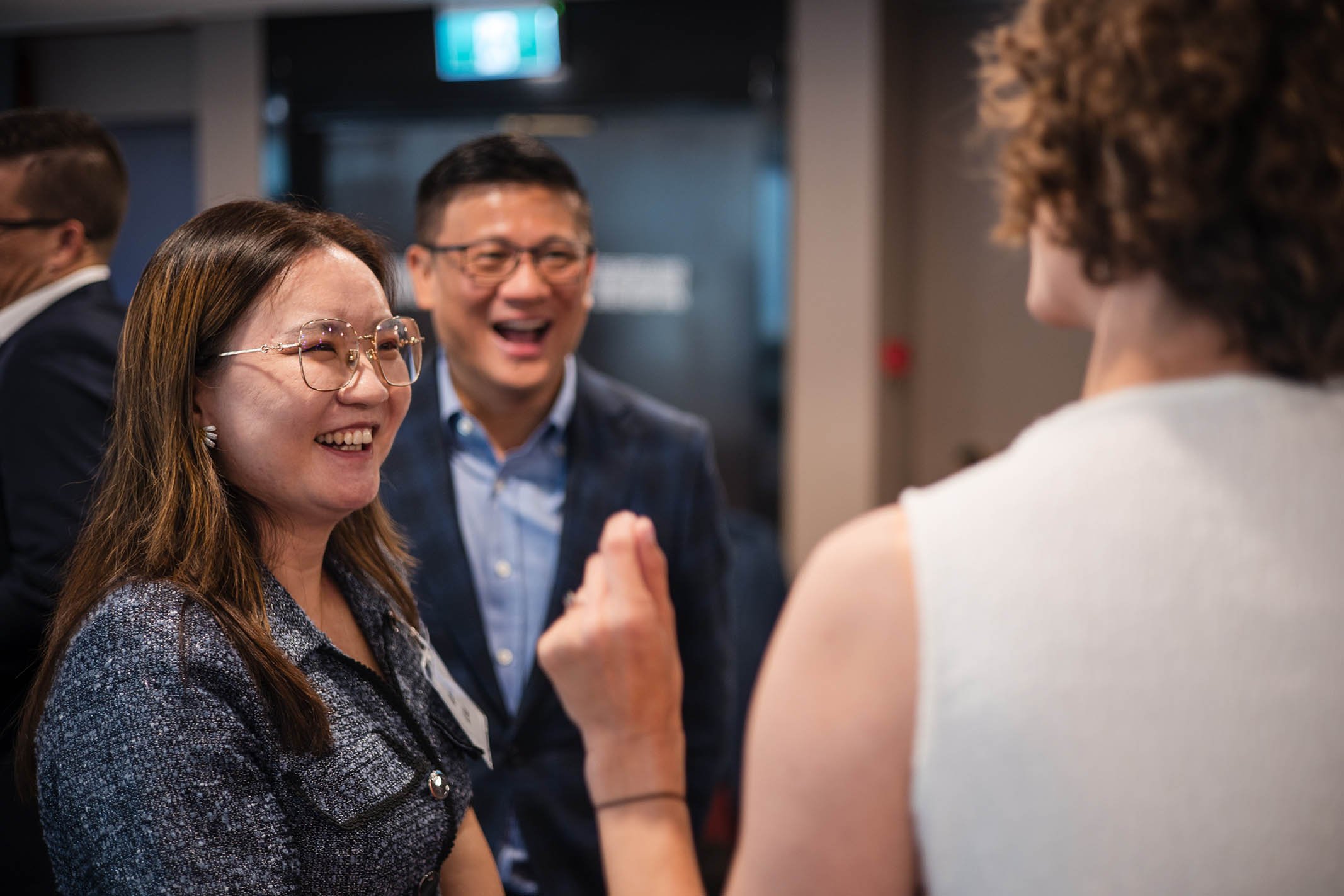 Three people laughing and smiling at a networking event or conference.