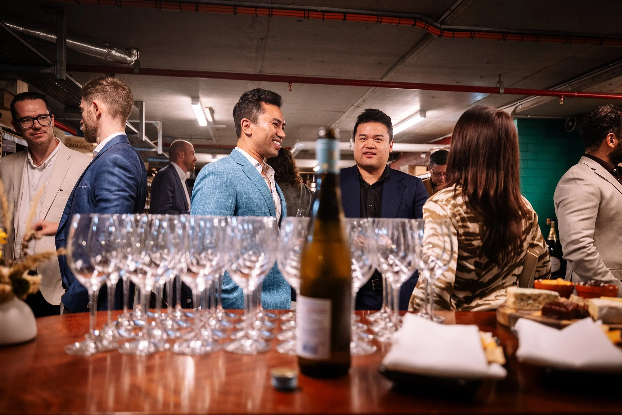 People socializing at a bar with glasses of wine and a bottle on the table.
