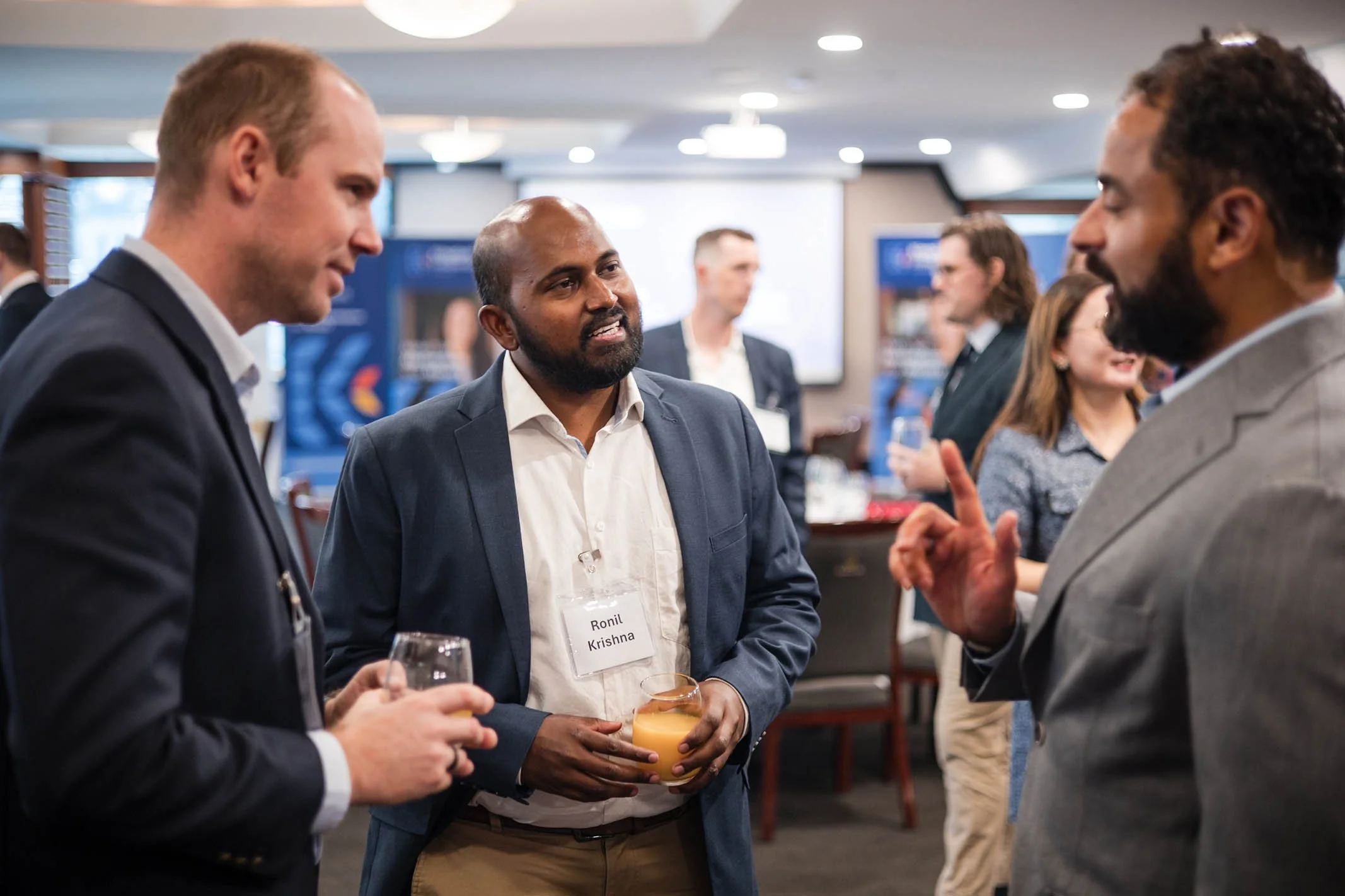 Three men in business suits having a conversation at a professional networking event.