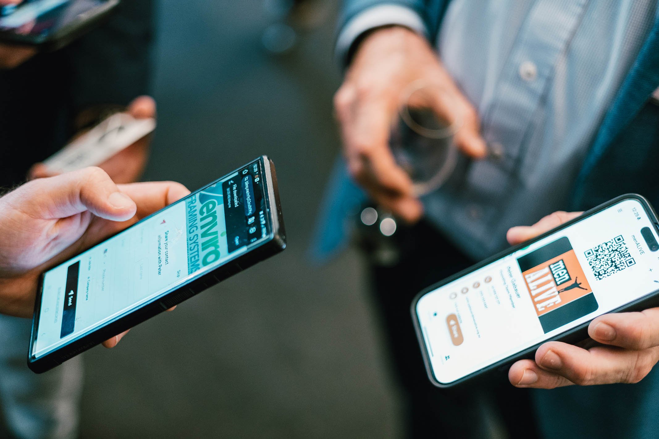 Two people holding smartphones displaying digital tickets, with a blurred person holding a beverage in the background.