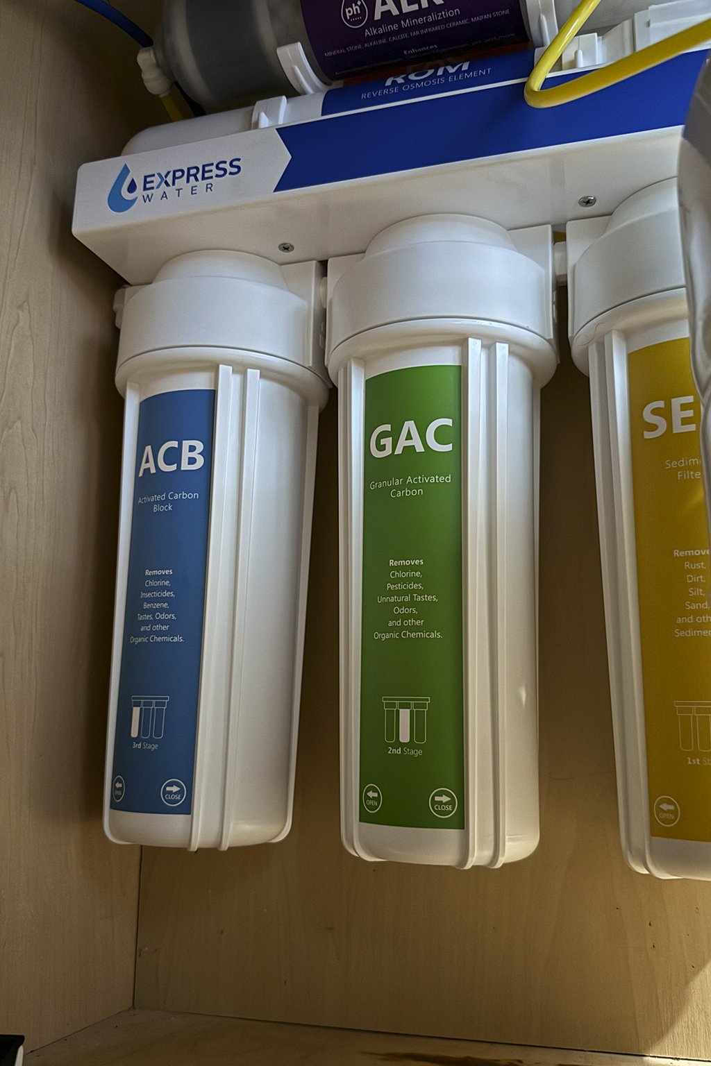 Water filter system with three cartridges labeled ACB, GAC, and Sediment.