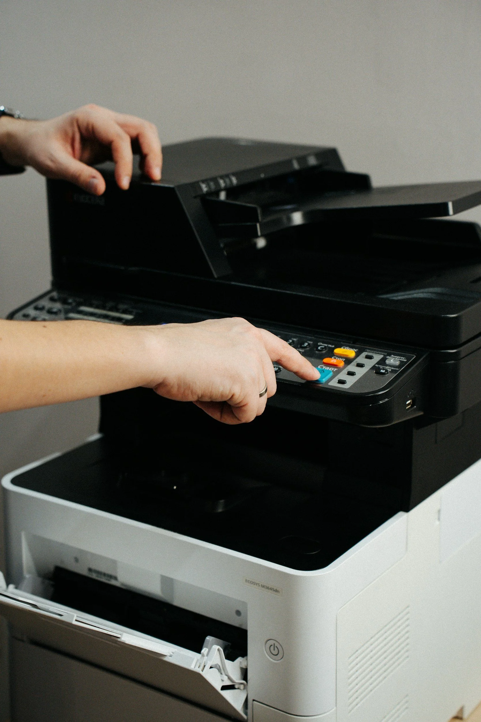 Person operating a multifunction printer and copier machine.