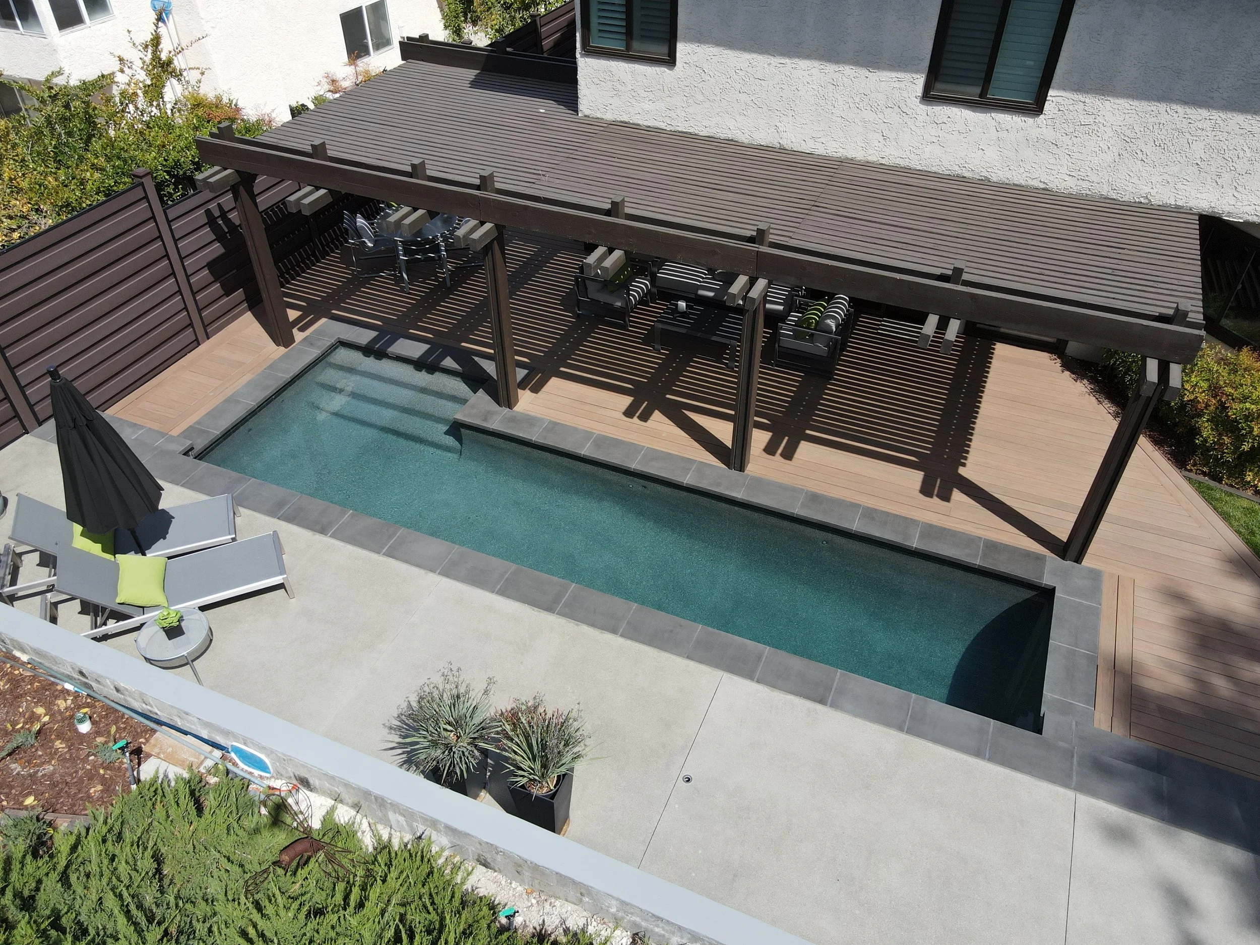 Backyard remodel with lap pool, custom wood deck, and pergola patio seating in modern home