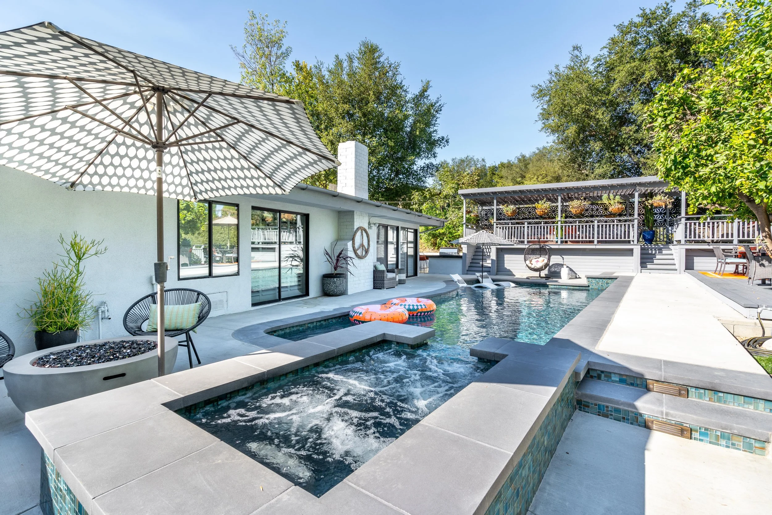 Custom backyard pool and spa with integrated hot tub, contemporary patio, shaded lounge area, and multi-level outdoor entertaining space.