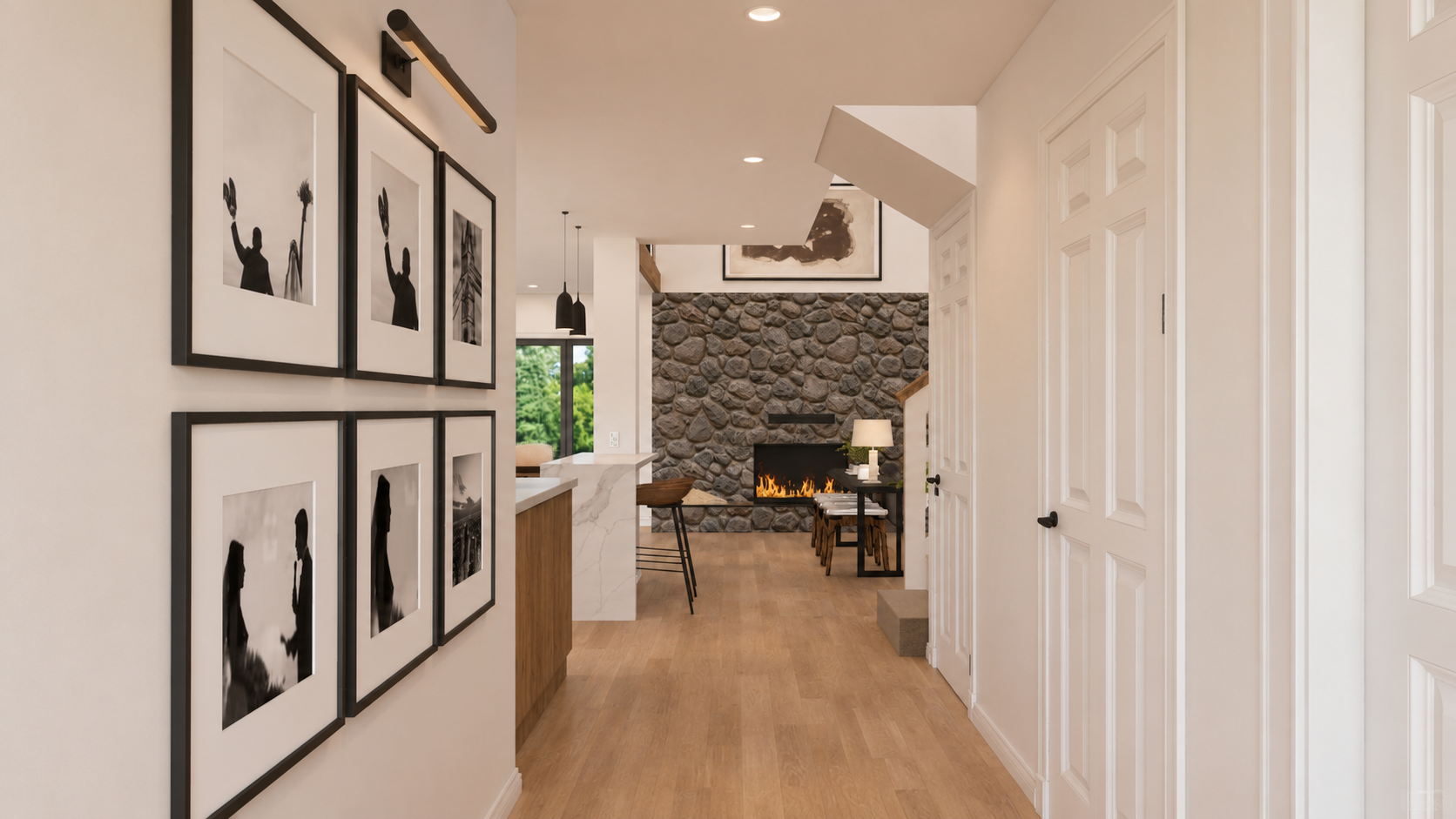 Modern remodeled hallway with gallery wall, warm wood flooring, white doors, open kitchen view, stone fireplace, and bright updated living space.