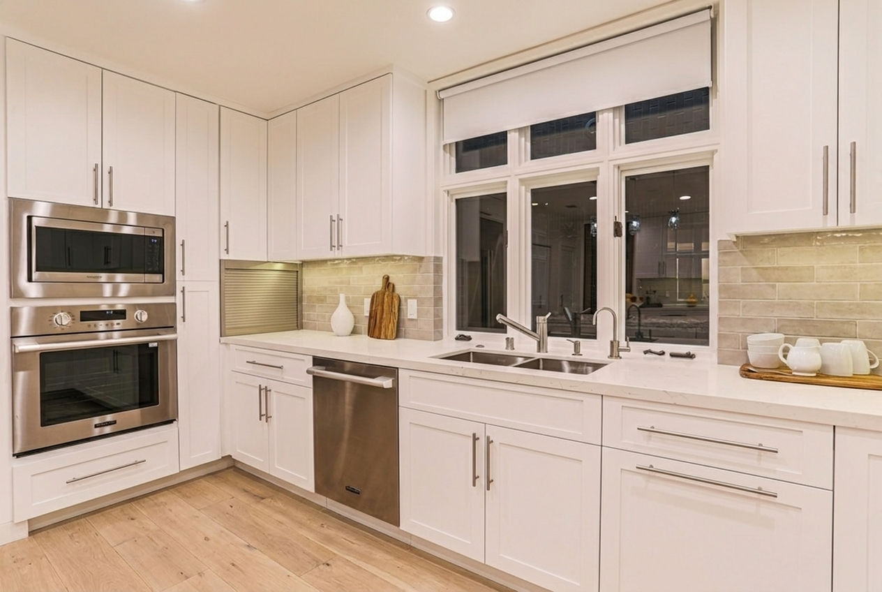 Custom white Irvine kitchen cabinetry with built-in beverage station, quartz countertops, and large windows providing natural light.