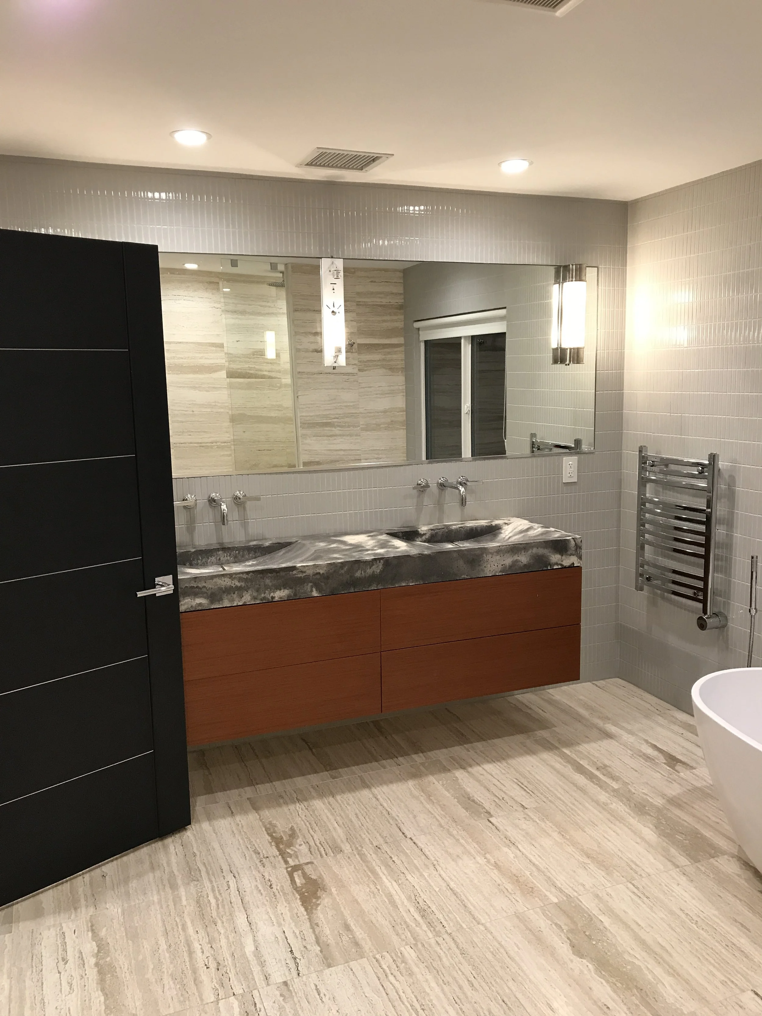 Modern bathroom remodel with floating wood vanity, stone countertop, wall-mounted faucets and large mirror