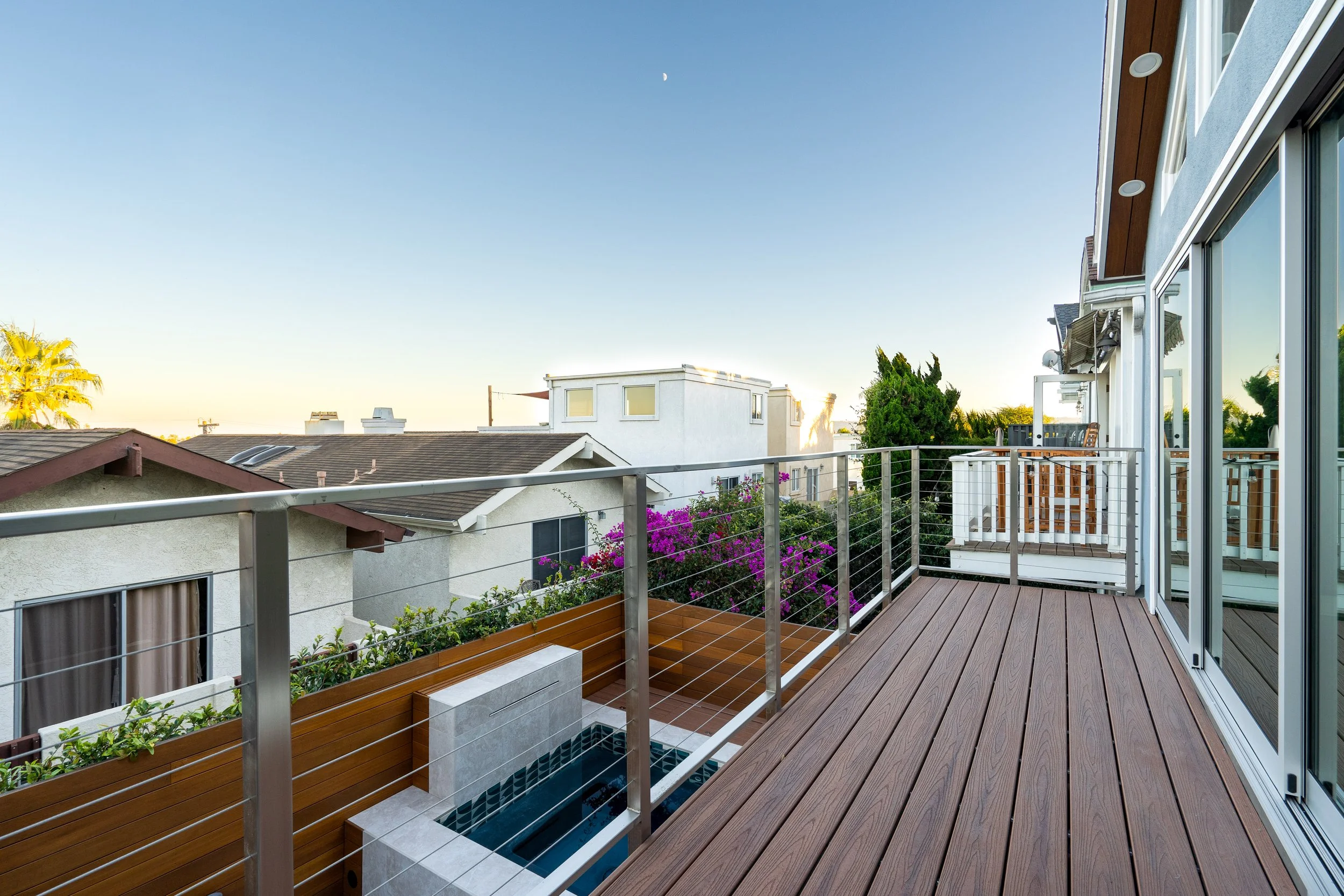 Contemporary backyard entertaining space with outdoor lounge area, modern hardscape, and elevated deck overlooking the property.