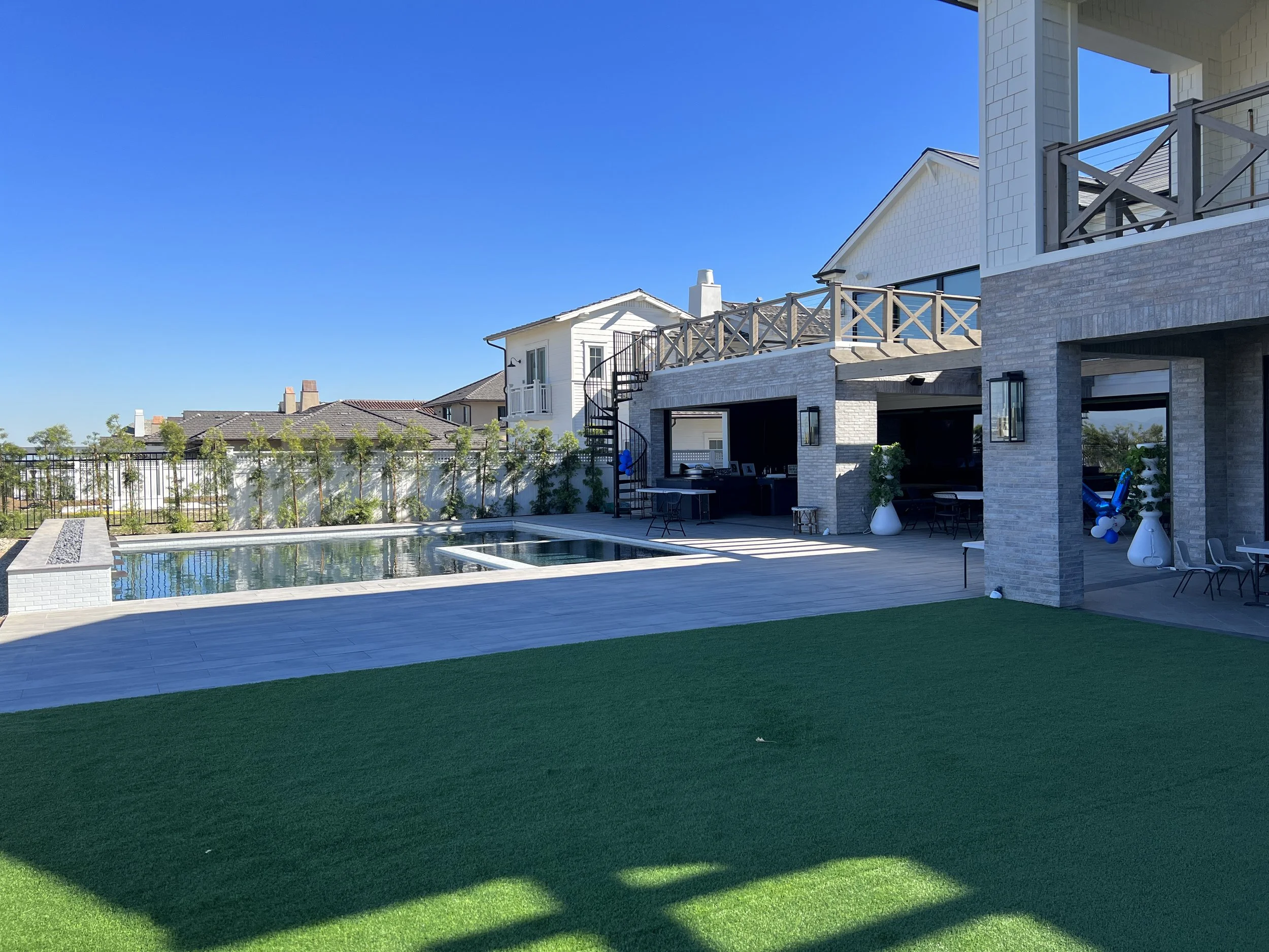 Luxury backyard remodel with pool and spa, outdoor covered patio, second-story deck, and modern coastal home design